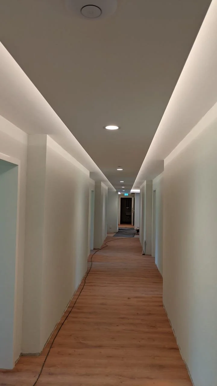 Leerer Hotelkorridor mit weißen Wänden und Holzfußboden, Deckenleuchten