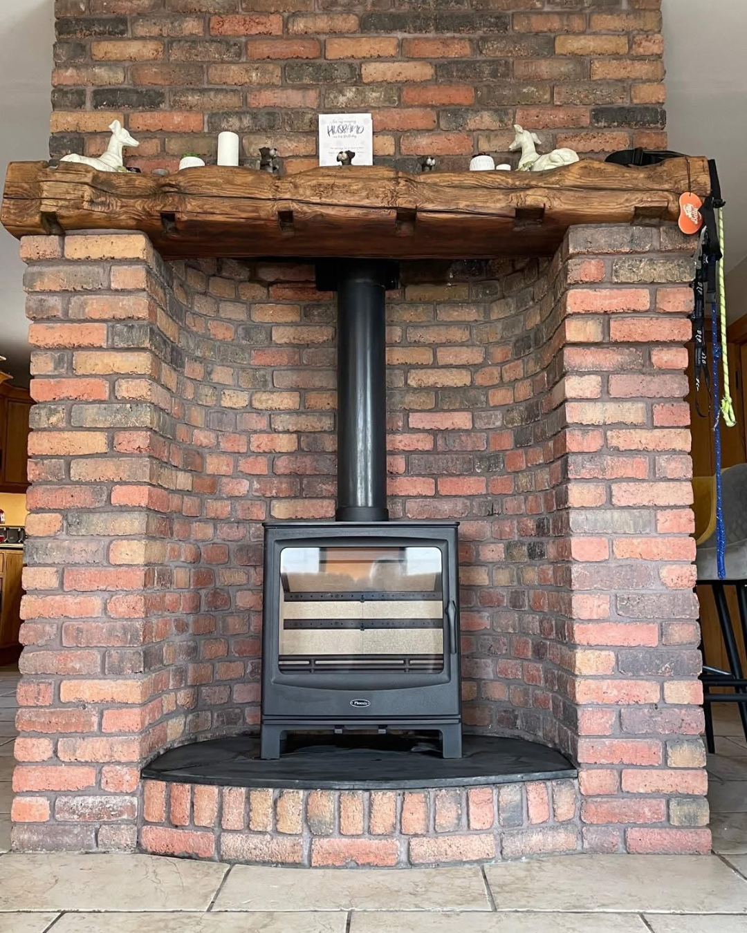 A cozy brick fireplace with a wood mantel and a wood stove insert in the center.