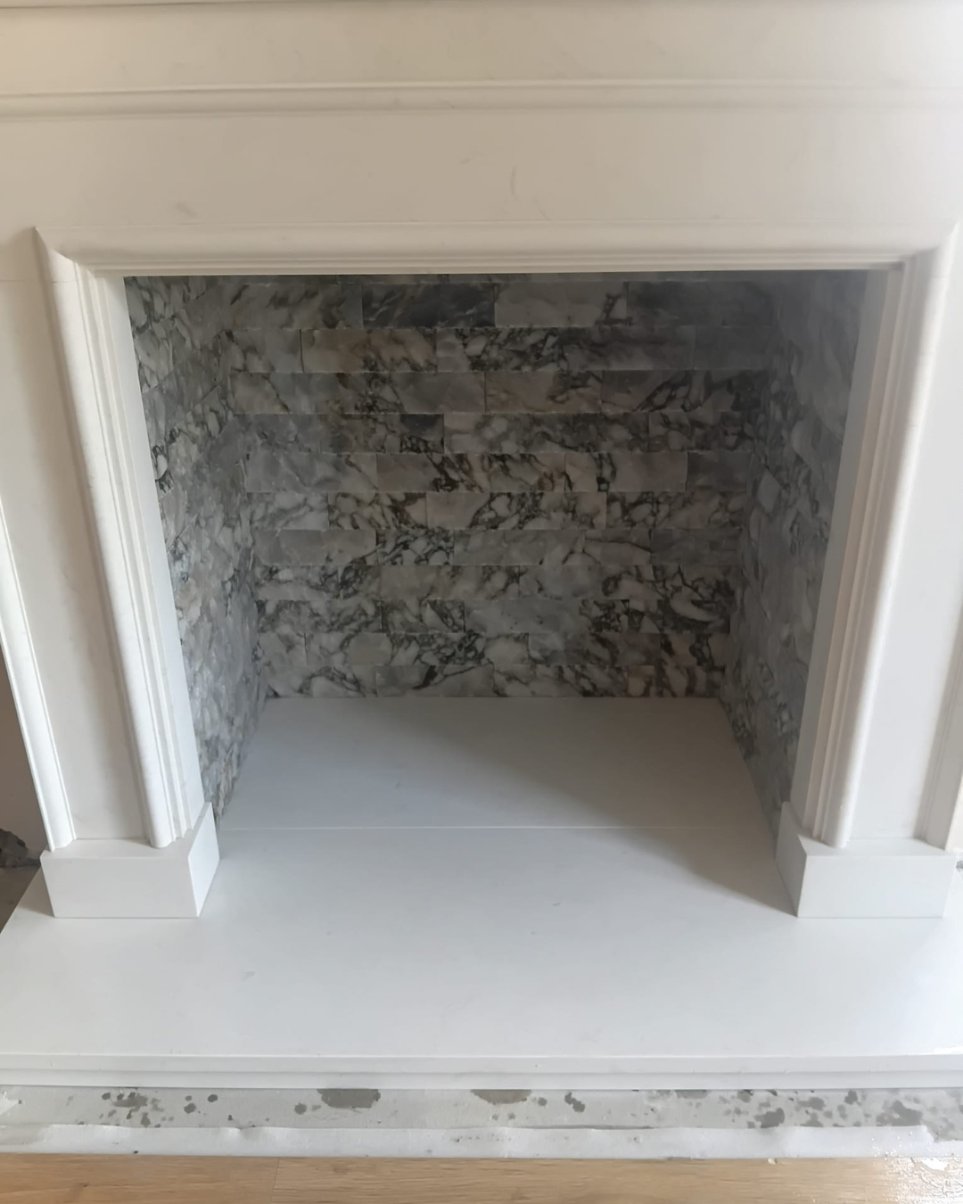 Empty fireplace with marble interior and white mantel.