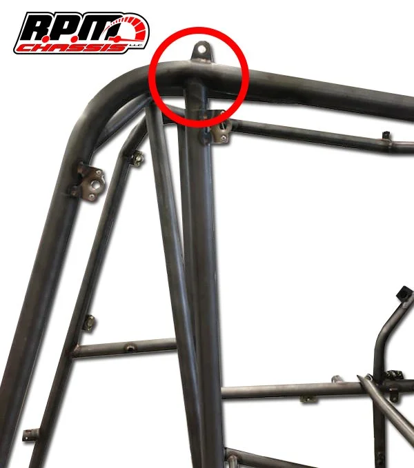 Close-up of a metal roll cage frame for a race car or off-road vehicle, with a red circle highlighting a mounting tab at the top. The image includes a logo that reads 'RPMS Chassis' in the upper left corner.