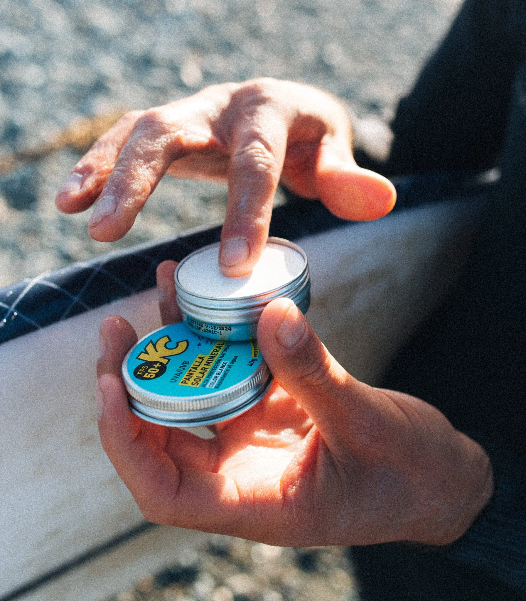 Produkt- und Brand Photography von einer Hand  die eine Dose mit Sonnencreme am Strand mit natürlichem warmen Licht hält.