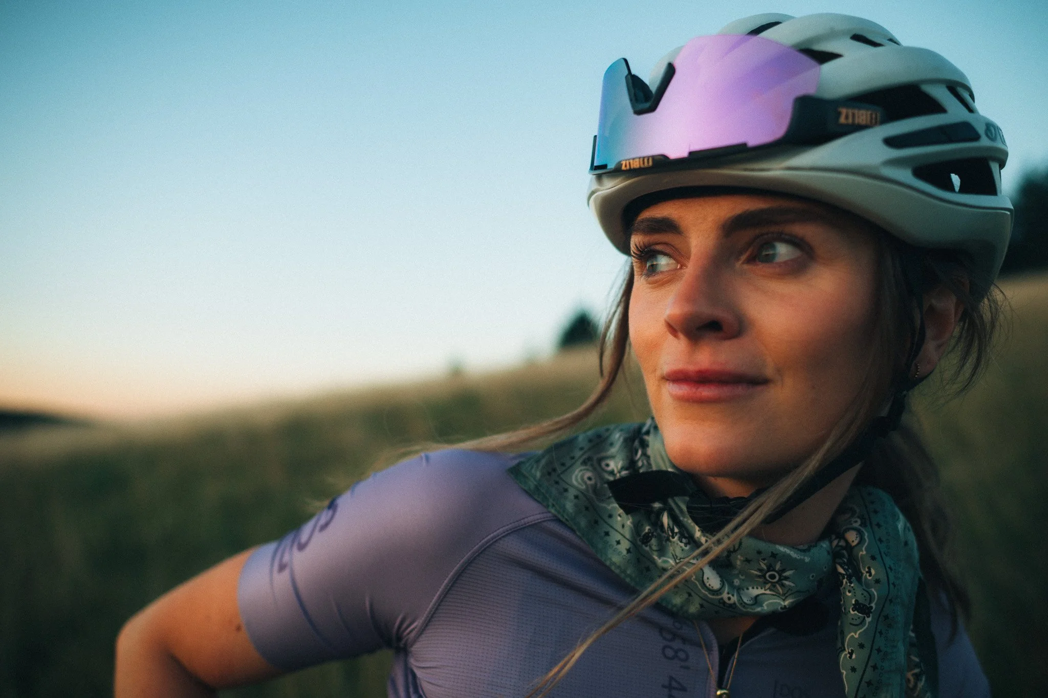 Natürliches Portrait einer  lächelnden Frau mit Fahrradhelm und Radsportkleidung, die im Freien bei Sonnenuntergang im Kaiserstuhl in Freiburg im Breisgau Fahrrad fährt.