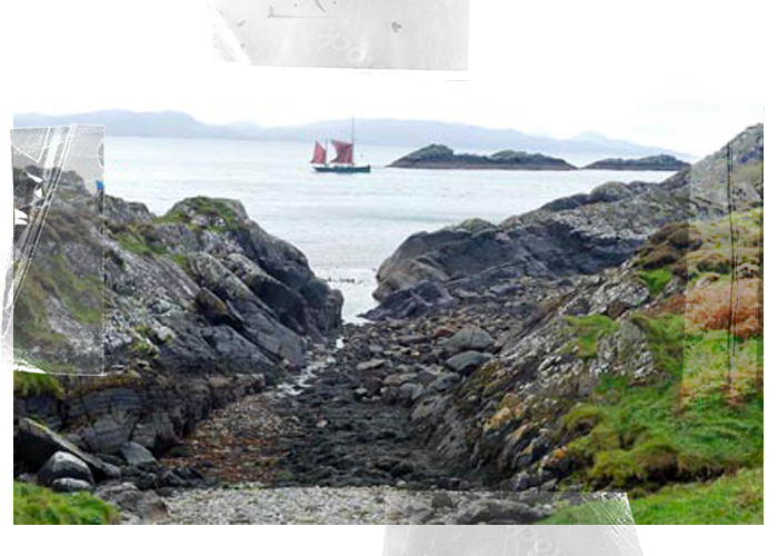 A rocky coastal area with a narrow path leading to the ocean, with a sailboat in the water and small islands in the background.