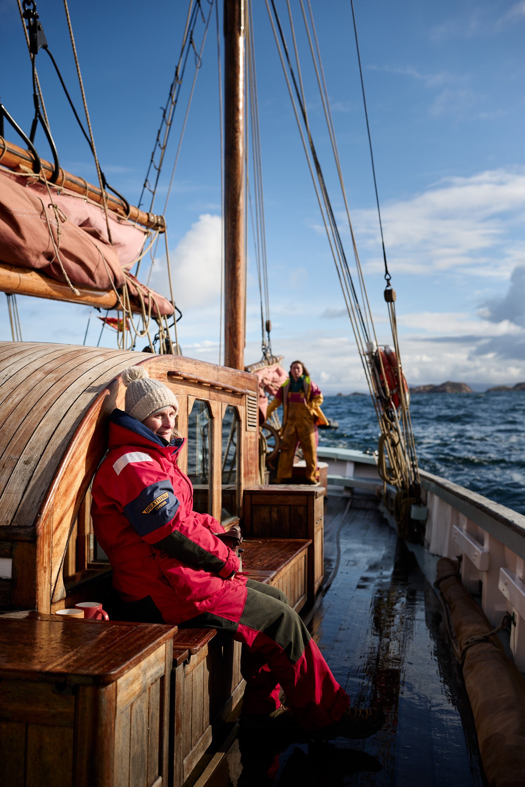 Woman at helm on Provident, guest relaxing on a sailing holiday on the Hebrides