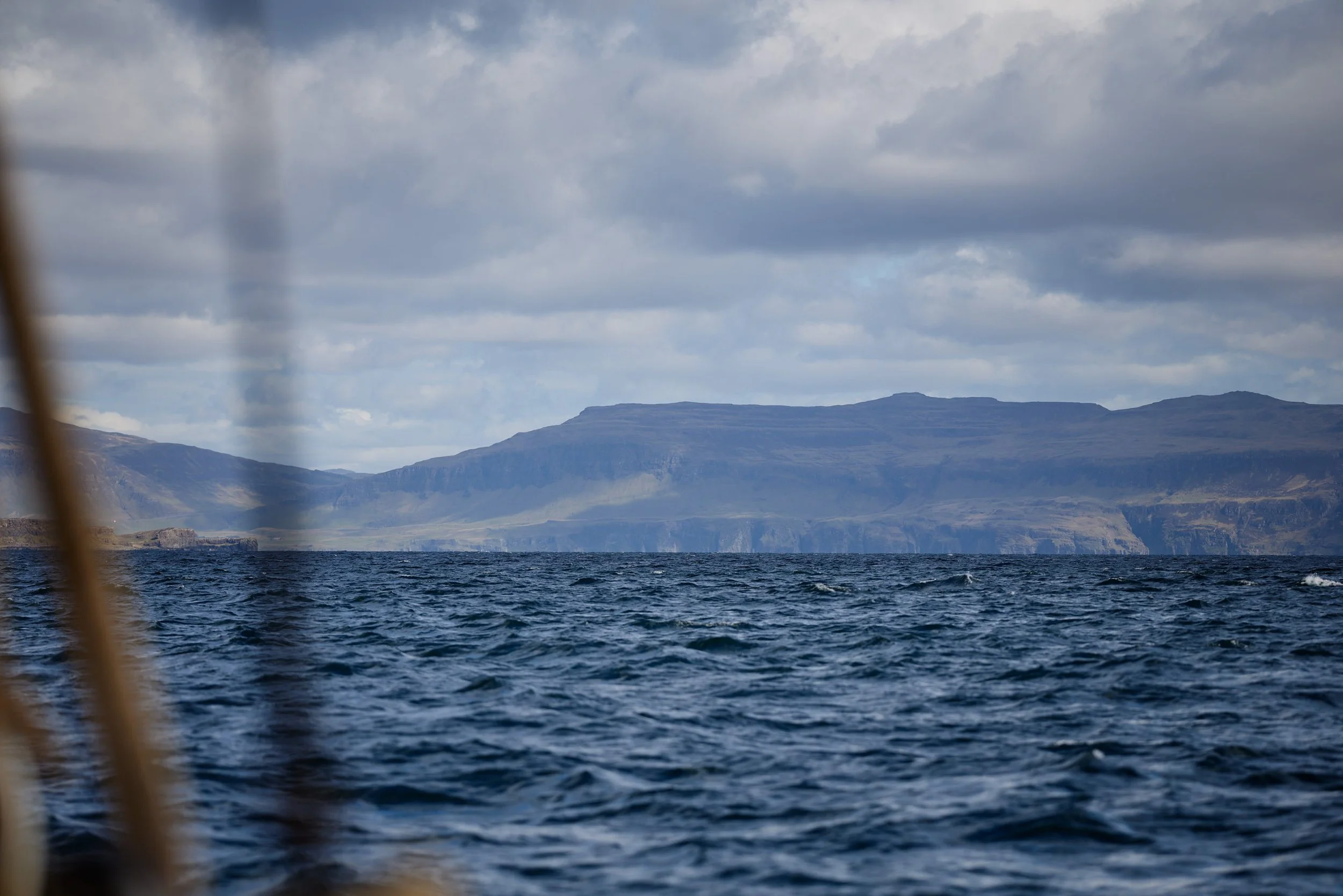 Scenic view of a body of water with mountains in the background and a cloudy sky.