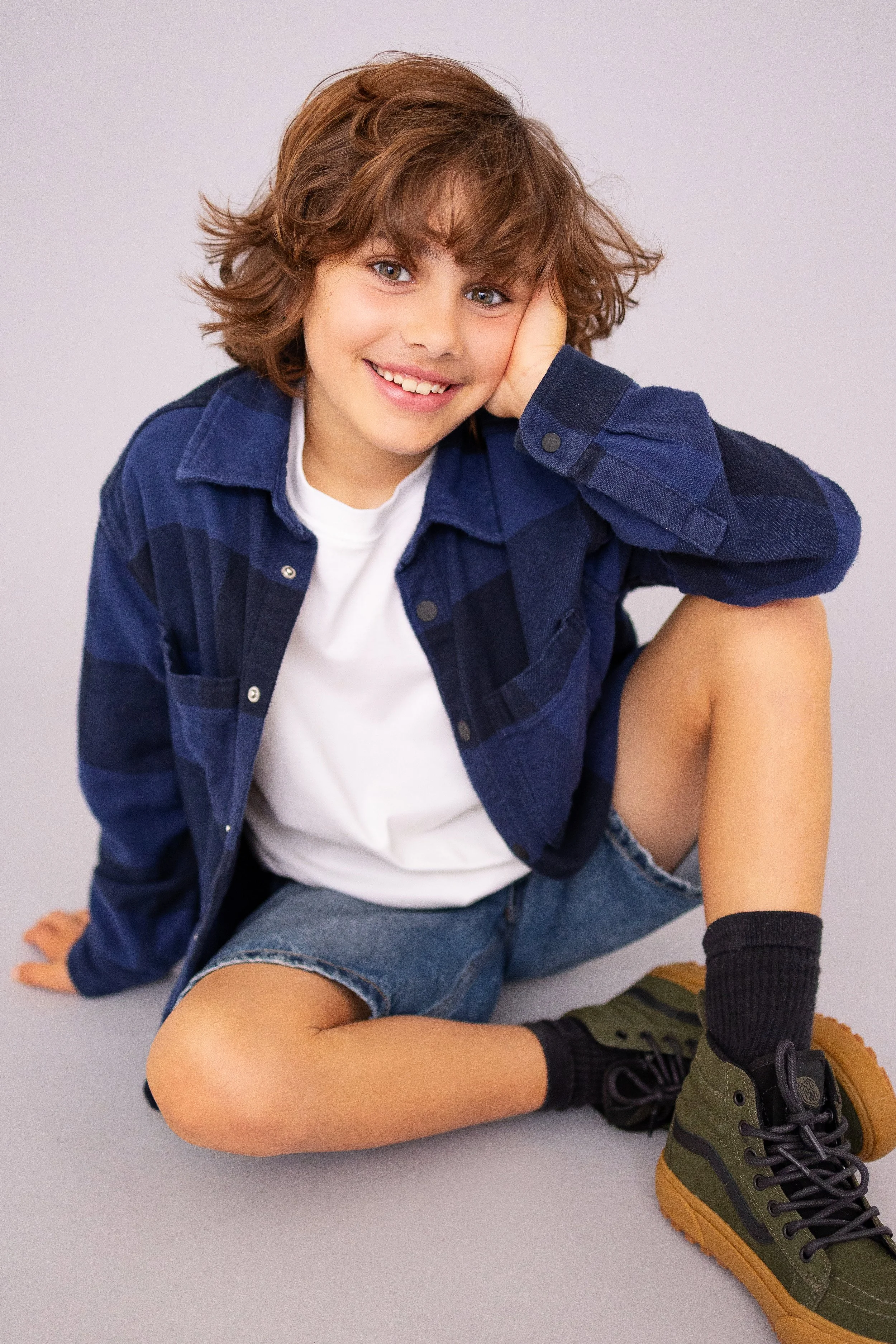 Young boy sitting and smiling naturally during a child model portfolio update session.
