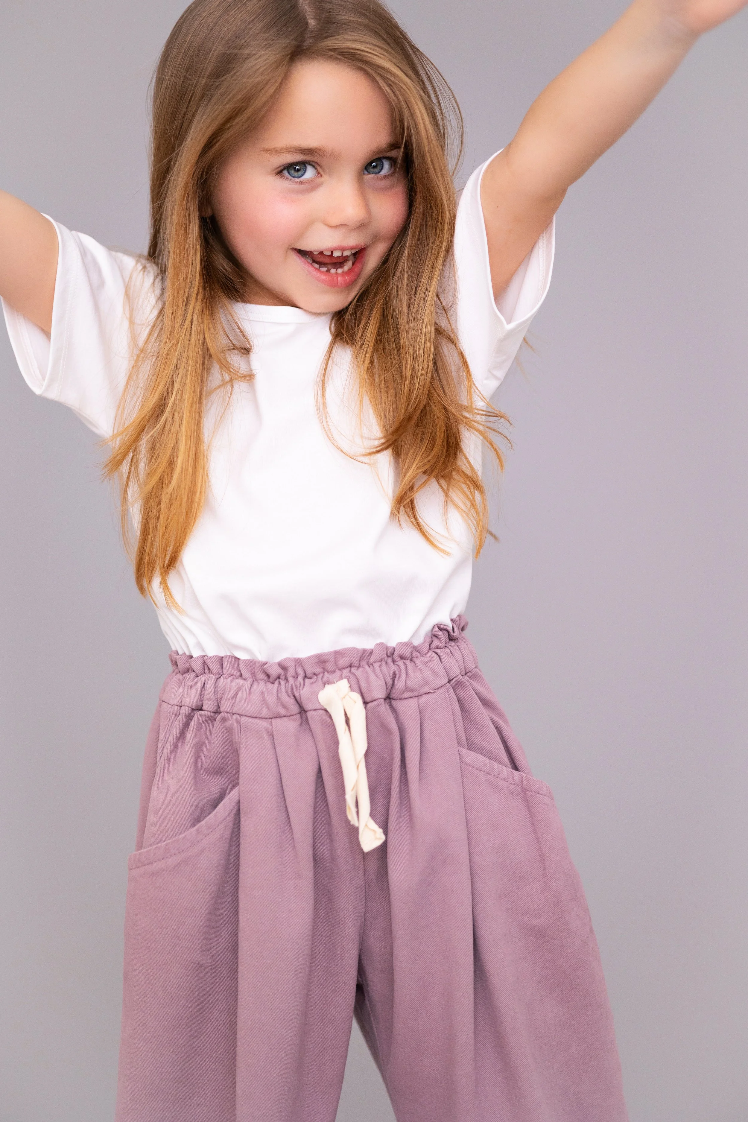 Full-length child model portrait of a smiling girl posing during a model portfolio update session.
