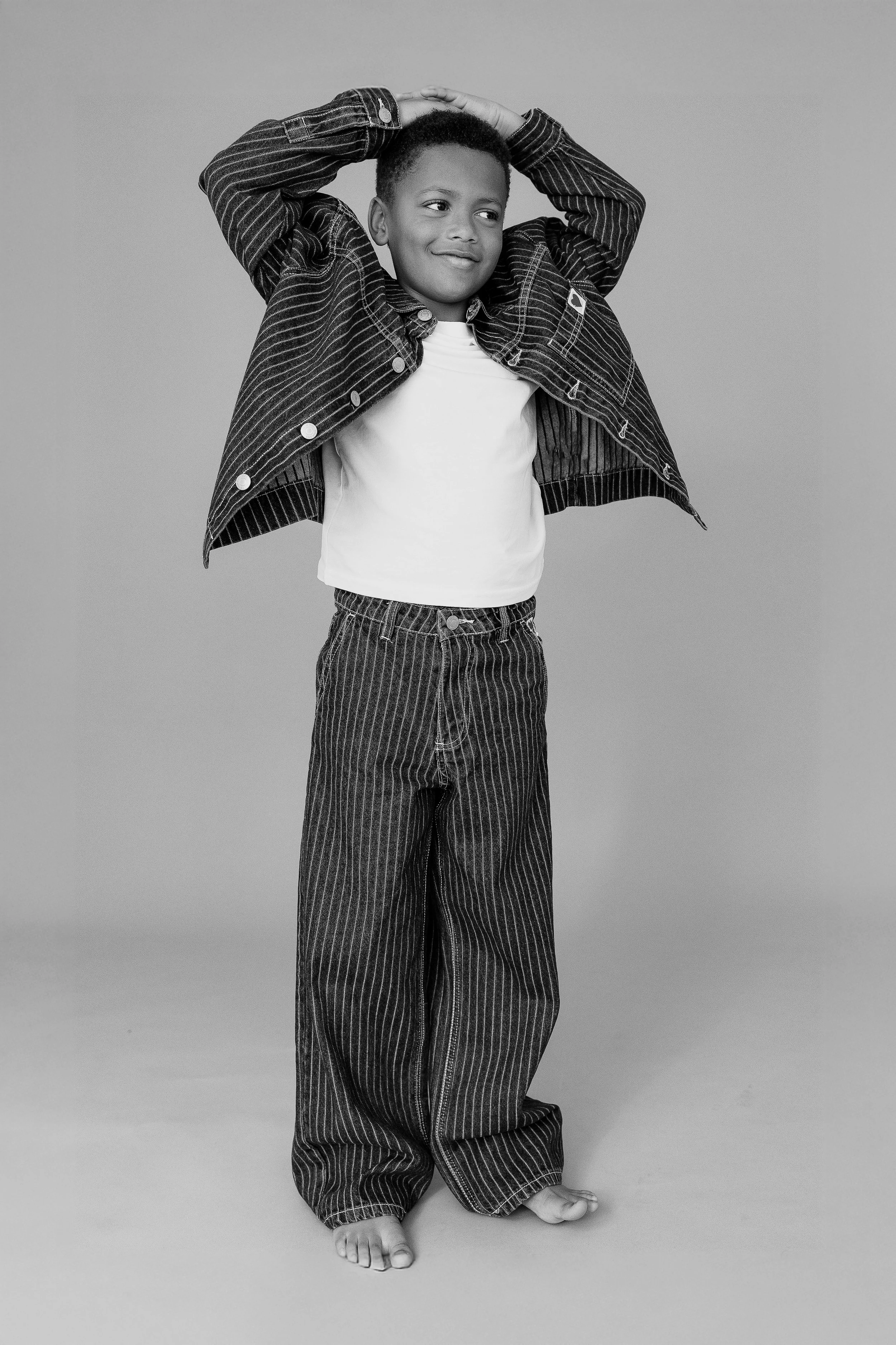 Full-length child model portrait of a young boy posing during a model portfolio update session.
