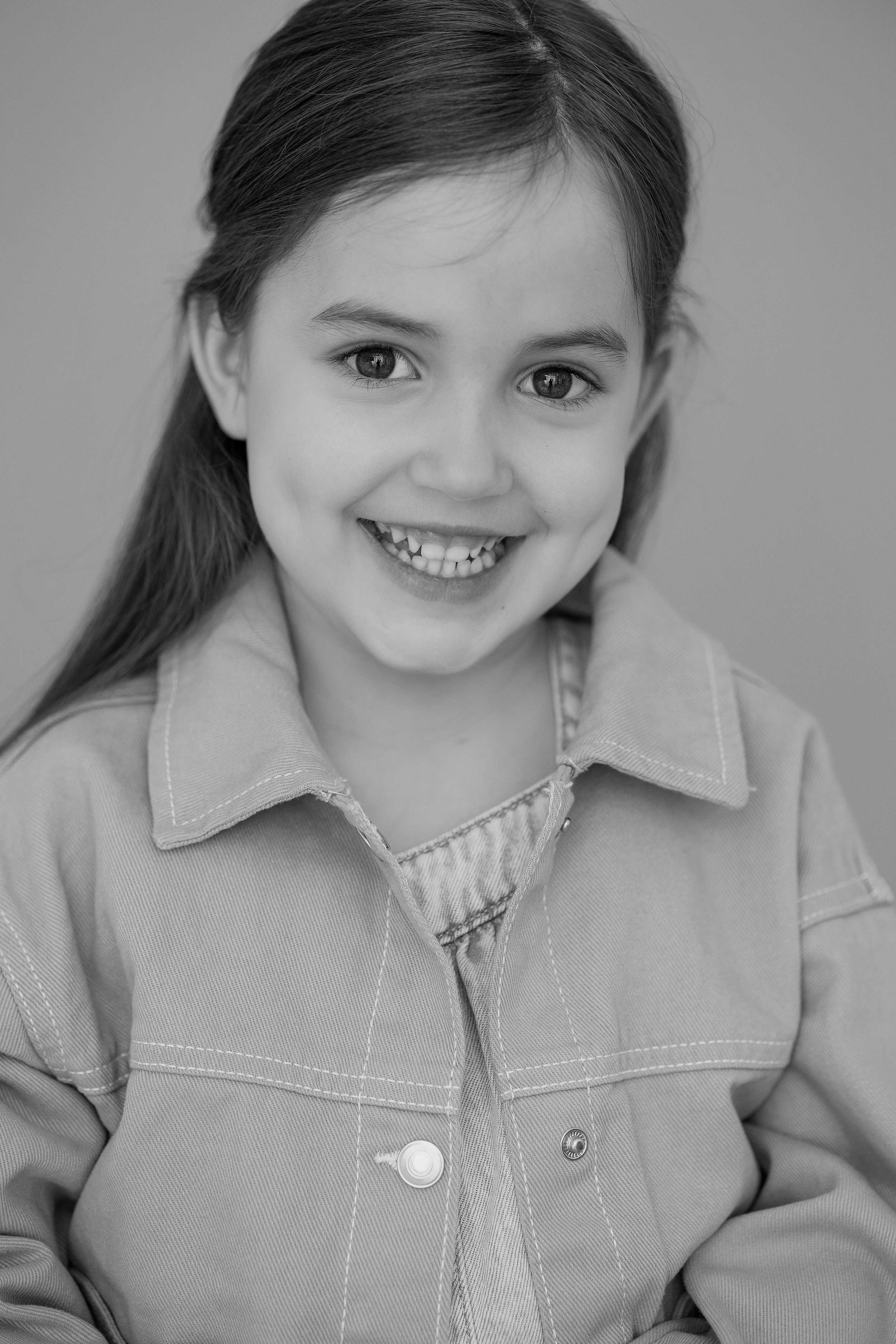 
Close-up black and white child model headshot with a bright, natural smile for a modelling portfolio update.
