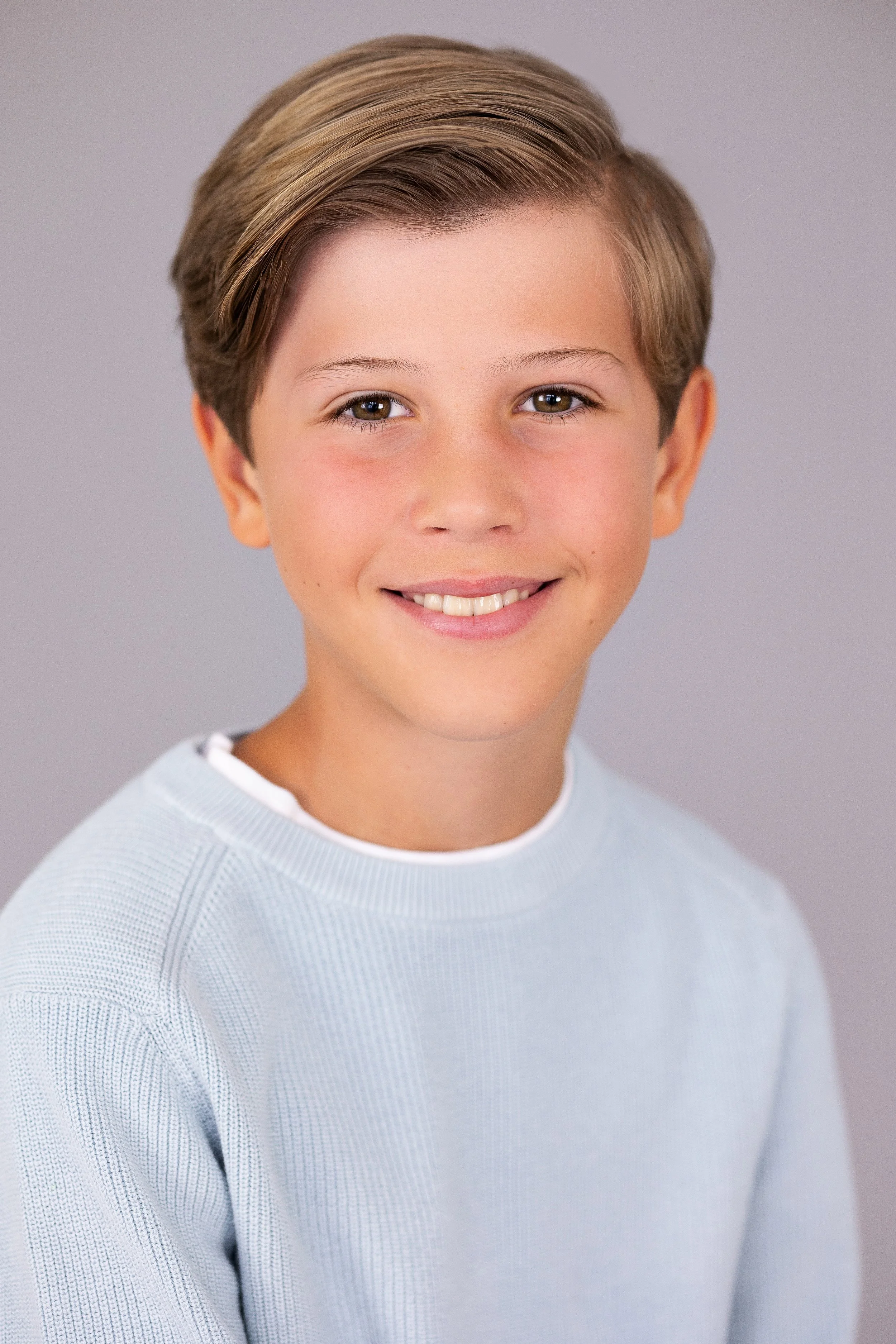 Smiling young boy during a natural child model headshot and portfolio update session.
