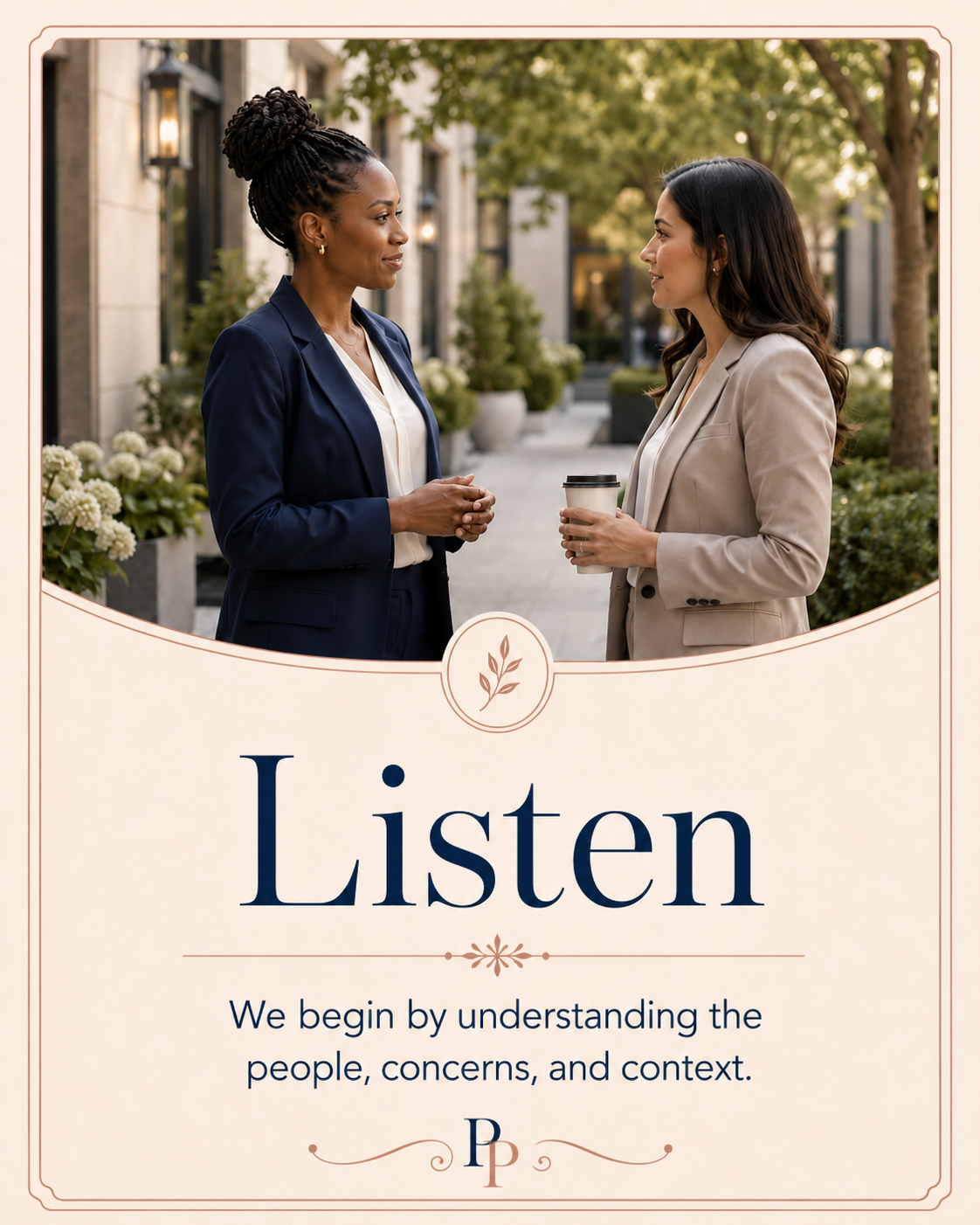 Two women in business attire standing outdoors, engaging in conversation, one holding a coffee cup, the other with hands clasped, against a backdrop of trees and potted plants.