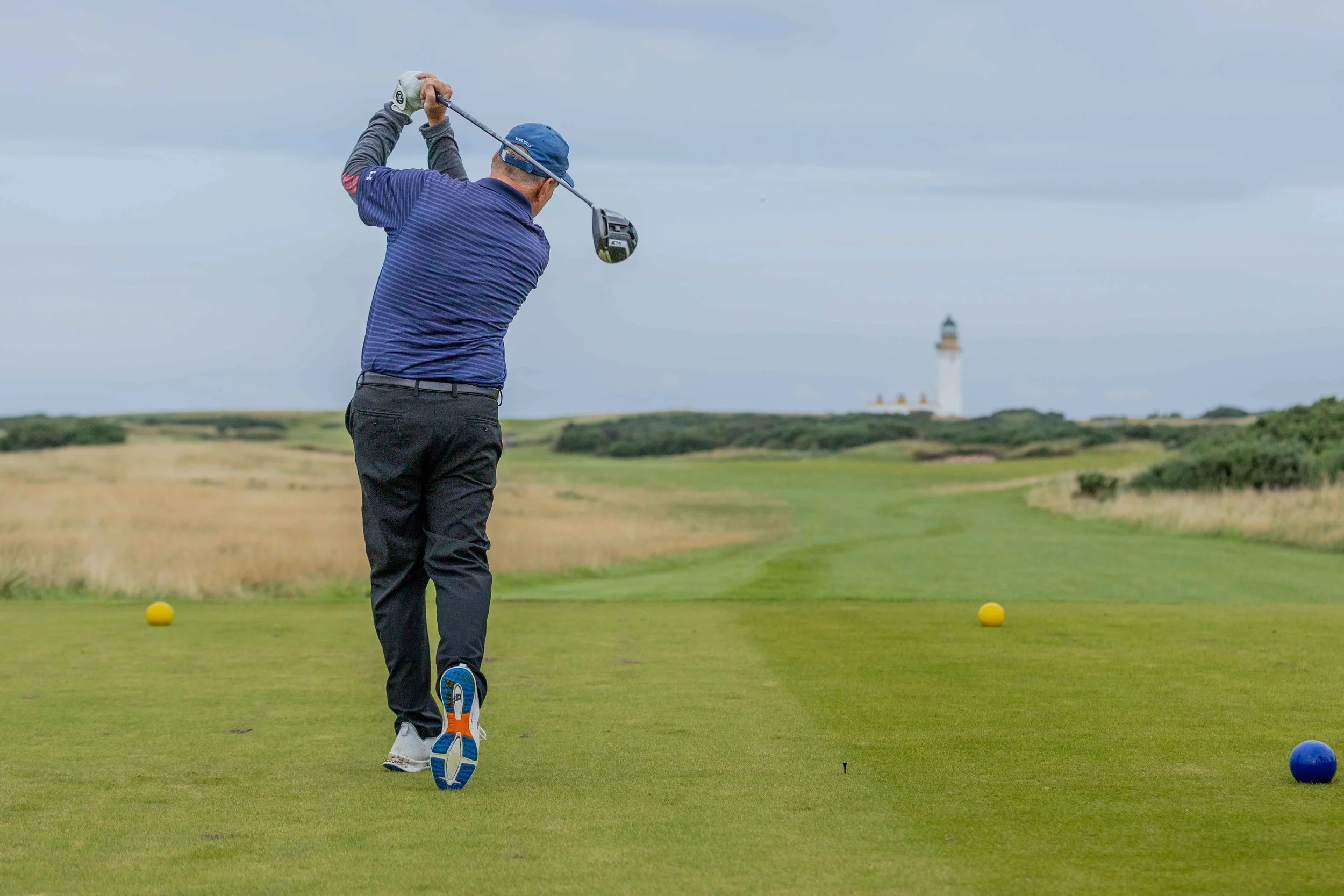 Picture of golfer driving at Trump Turnberry with he lighthouse in the background
