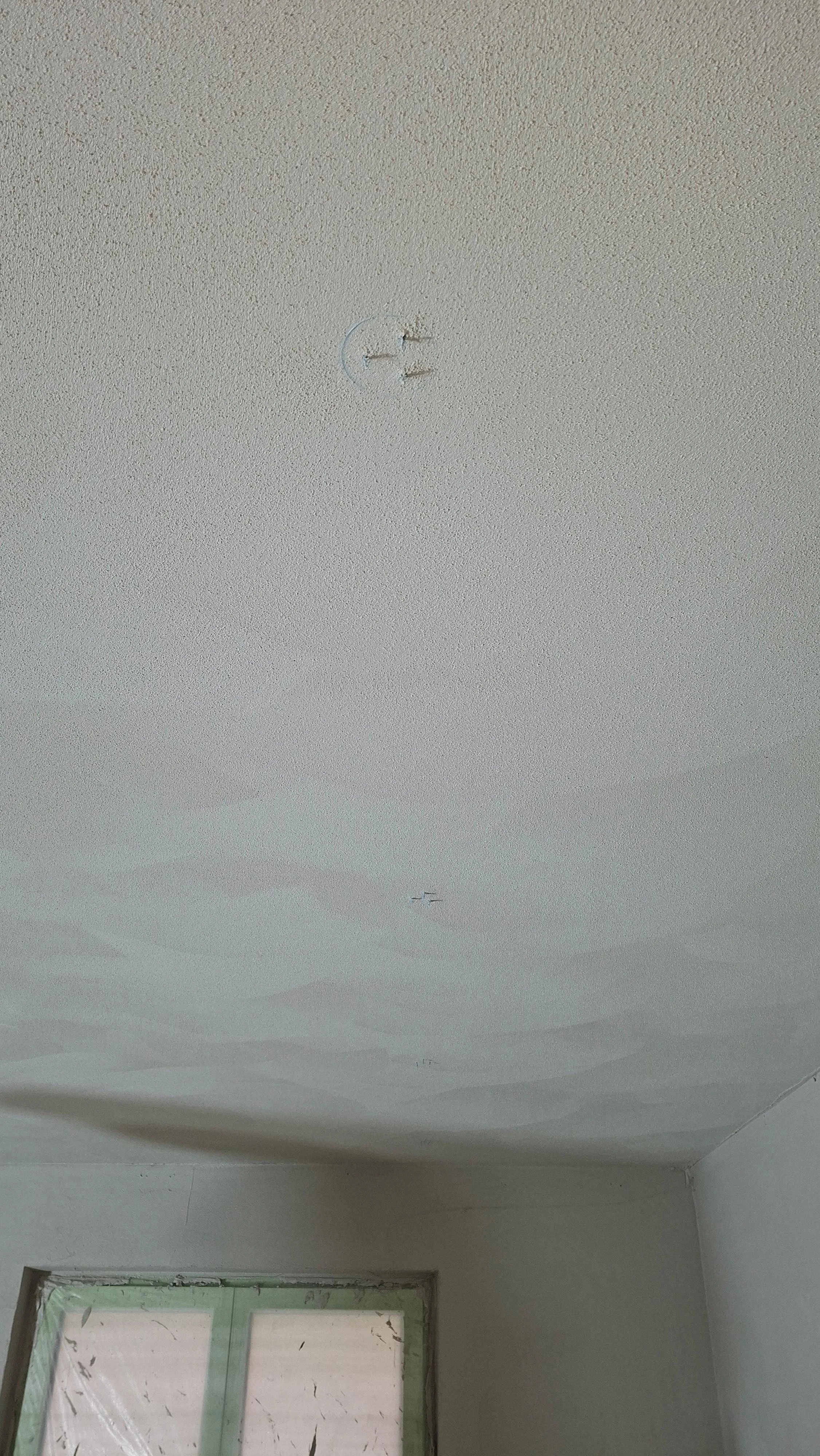 Verputzte Betondecke wo die Auslässe für die Einbaustrahler anhand der Signalborsten des Signaldeckels sichtbar sind.