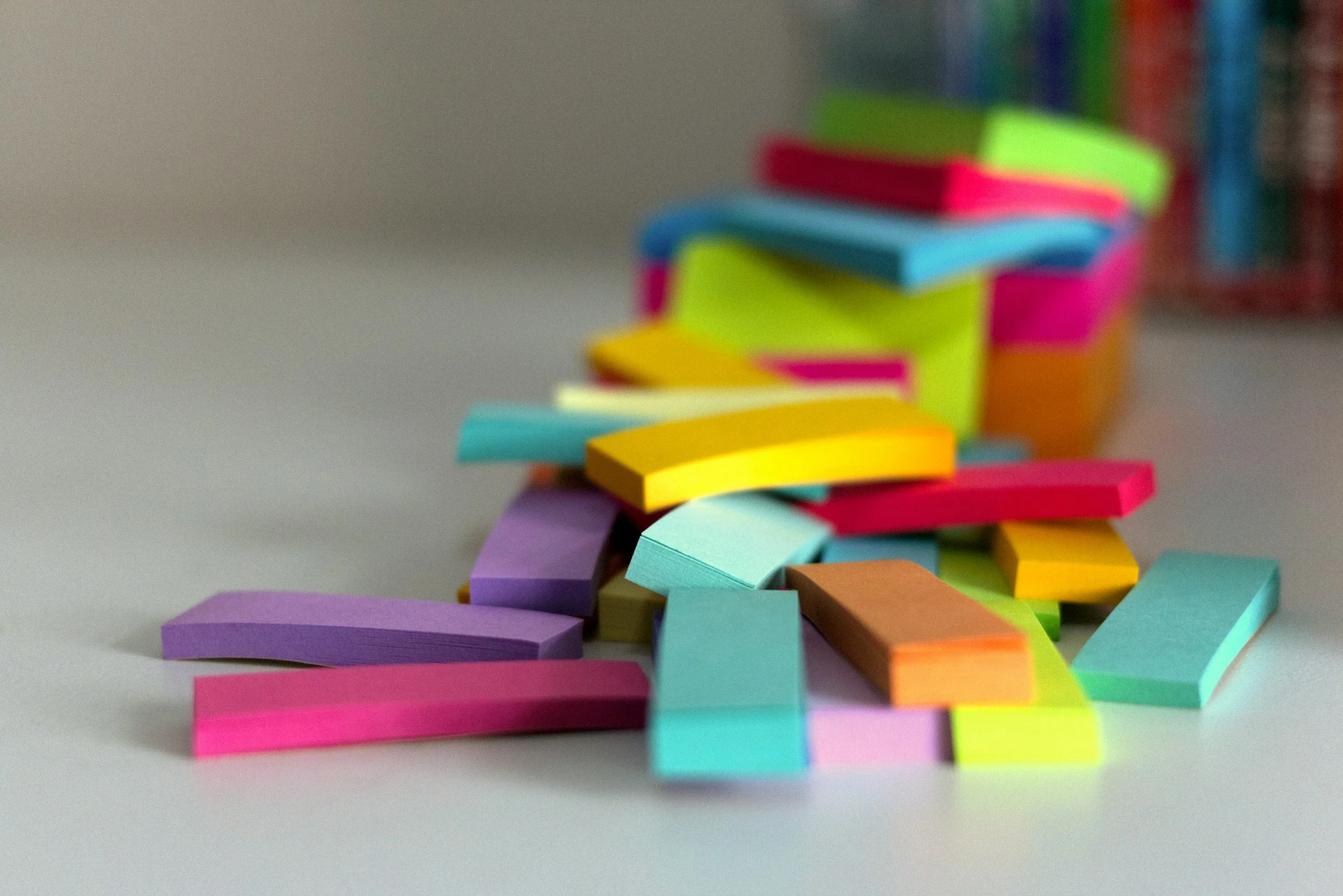 Colorful sticky notes arranged in a chaotic tower on a white surface.