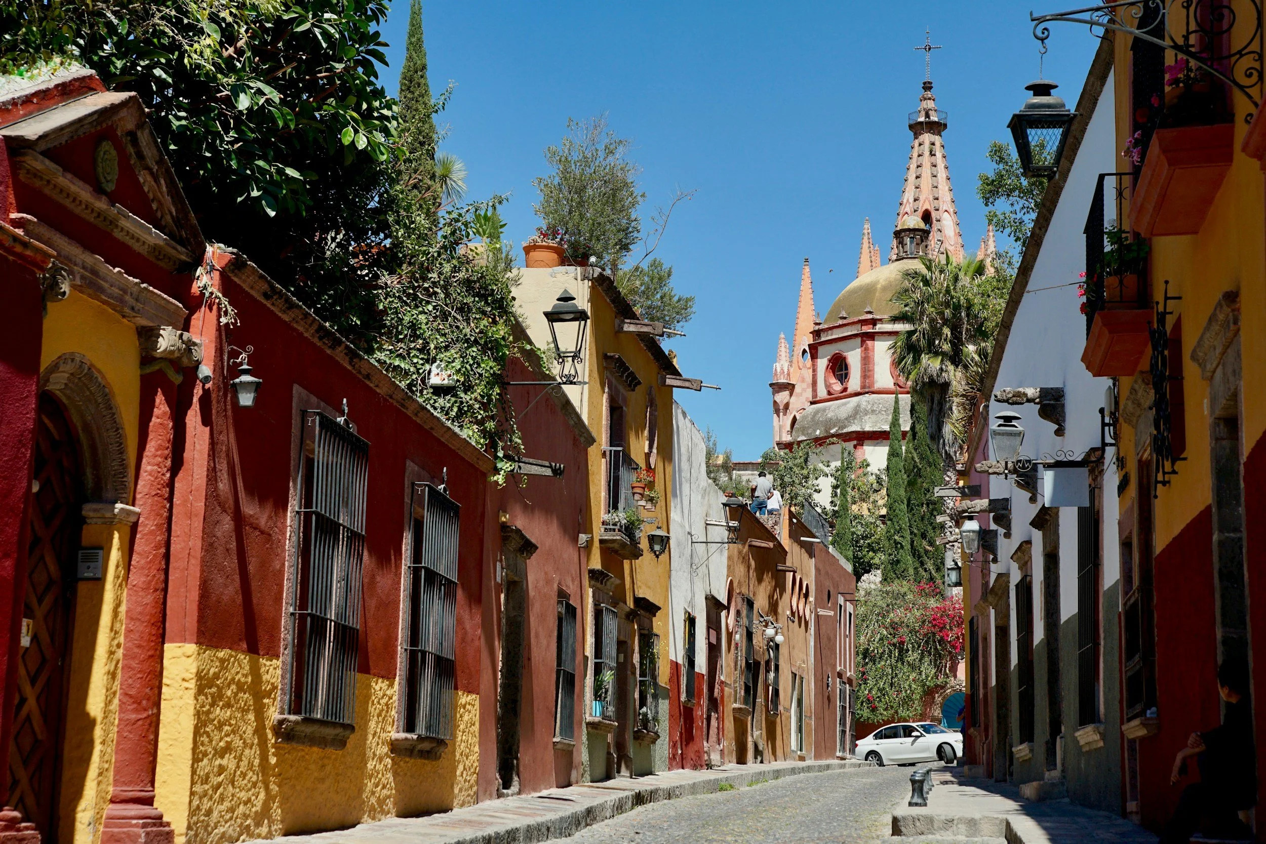 Colorful colonial buildings and church tower along a cobblestone street in Mexico.