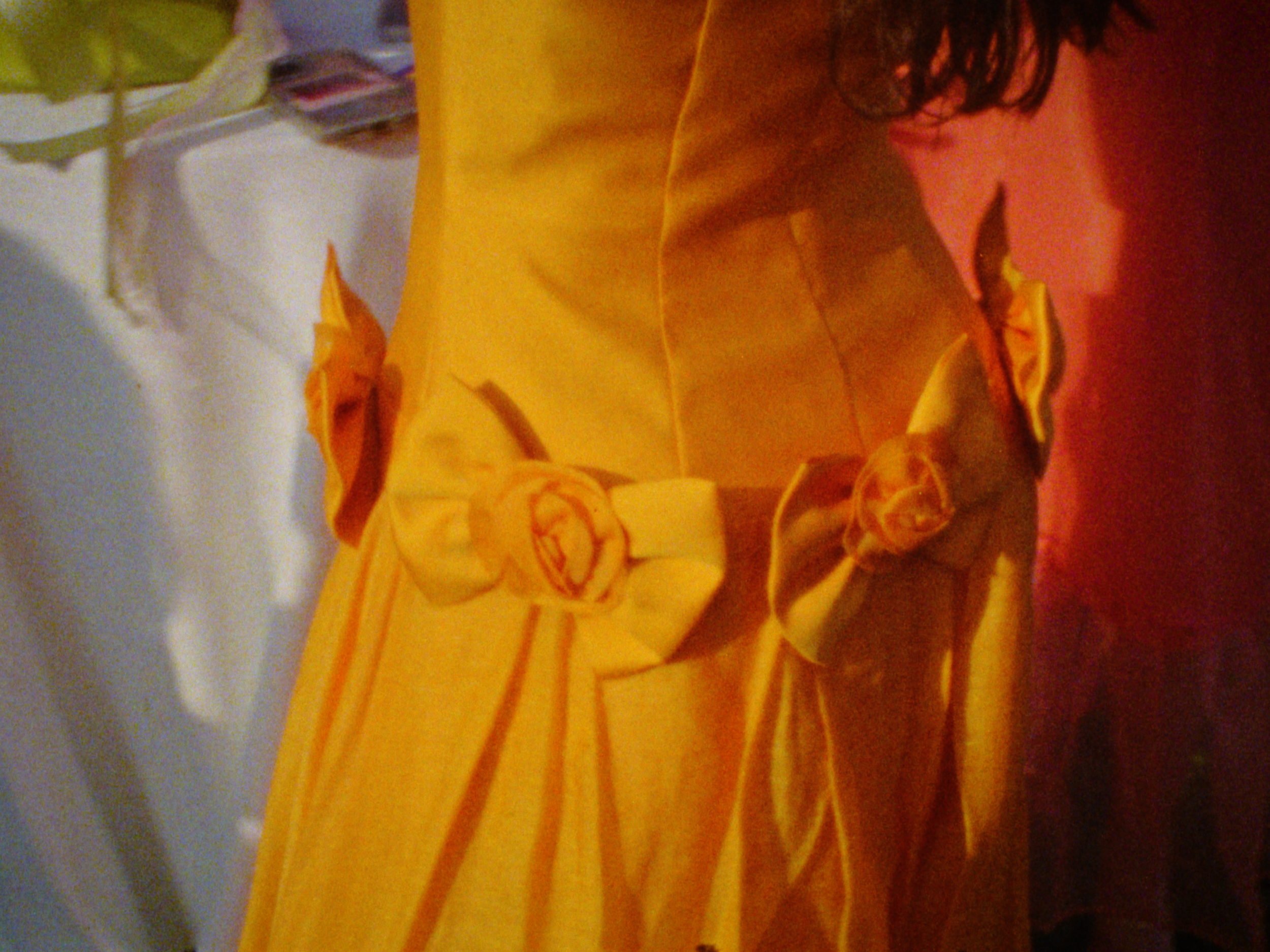 Close-up of a yellow fabric with orange and red embroidered designs, possibly a blanket or clothing, with a blurred background.