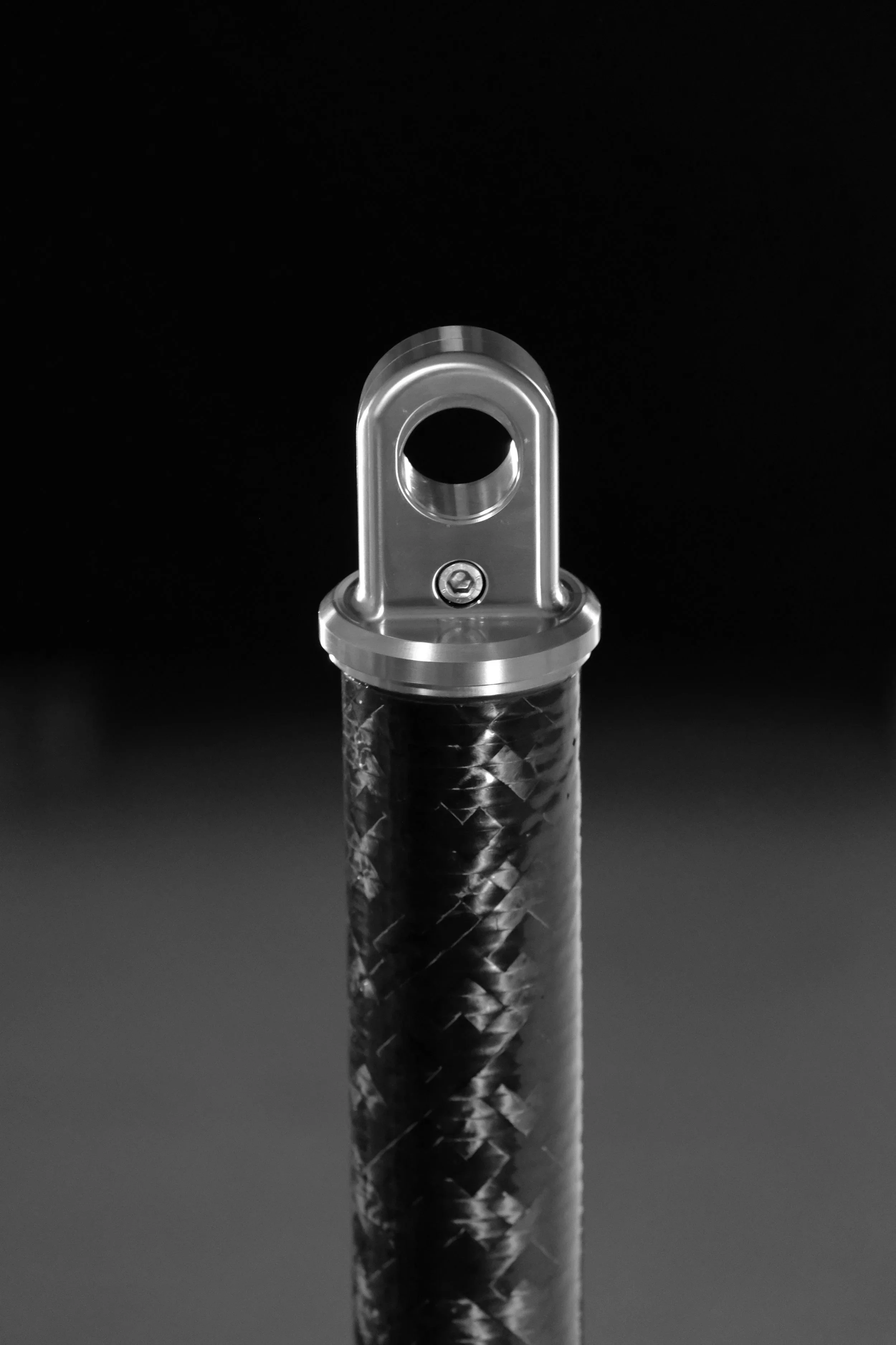 Close-up of a metallic flashlight head with a textured handle against a black background.