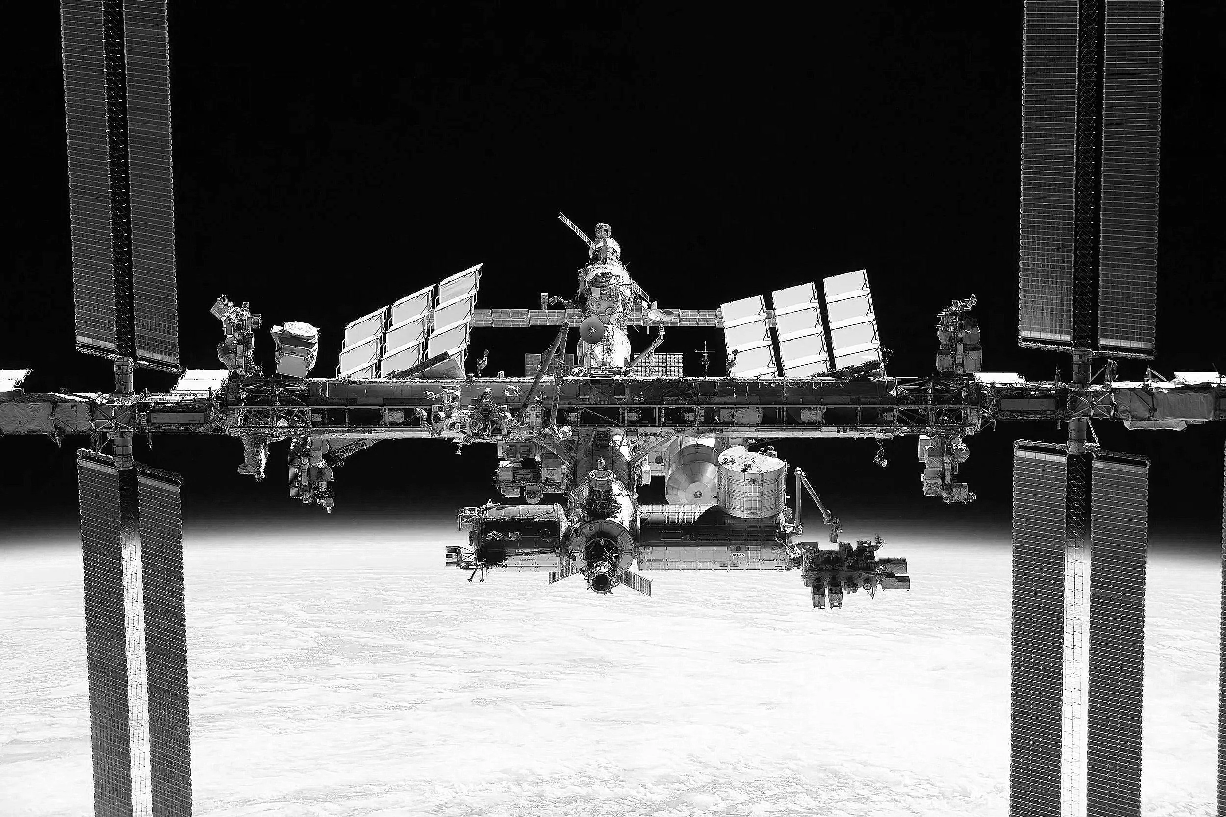Black and white photo of the International Space Station orbiting Earth.