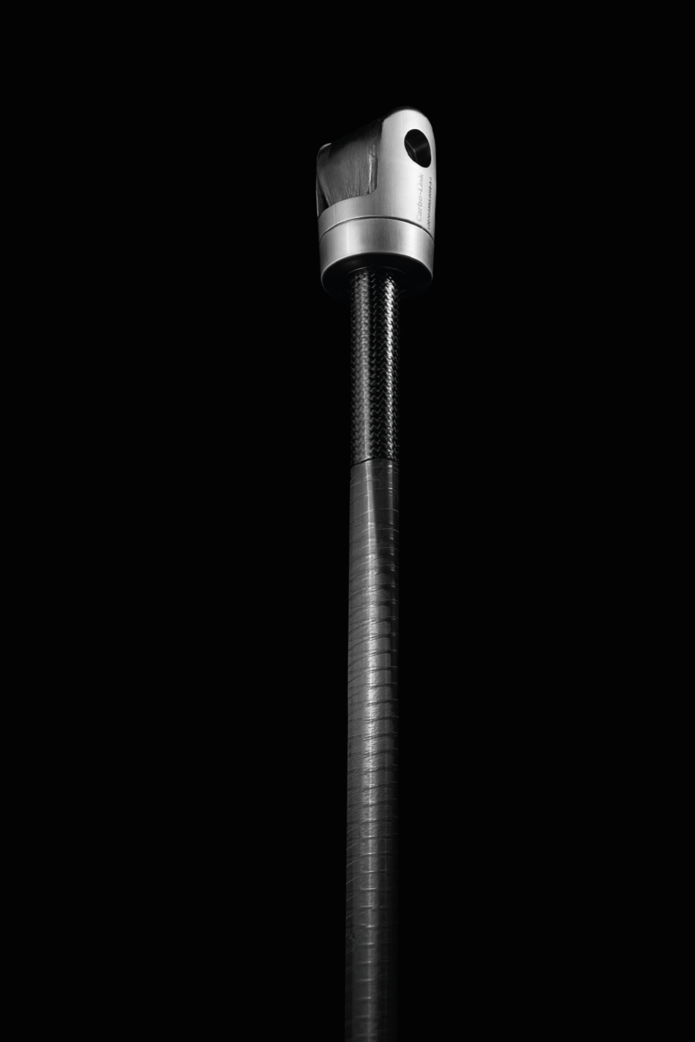 Close-up of a metallic element with a black background, a cylindrical textured body, and a rounded rectangular upper part with a small black hole.