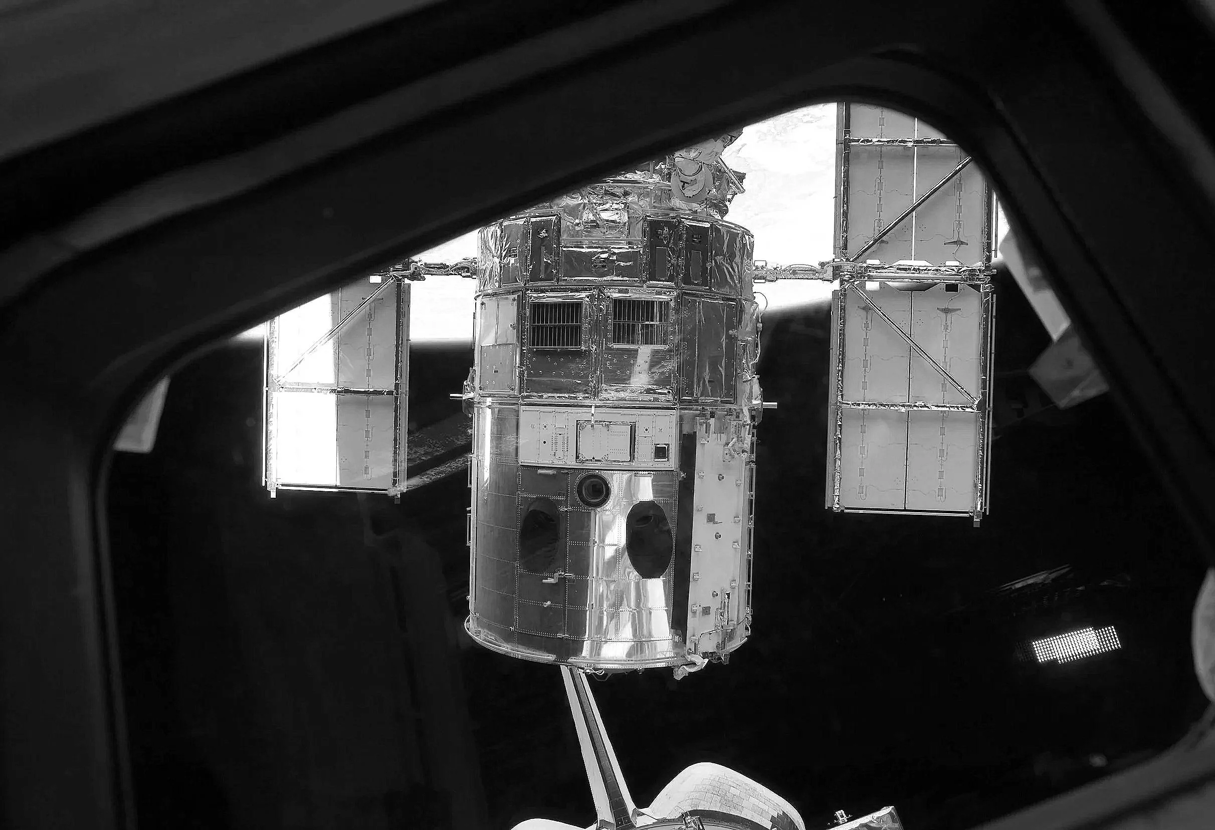 A spacecraft in space, viewed through a partial window or hatch, with earth visible in the distance.