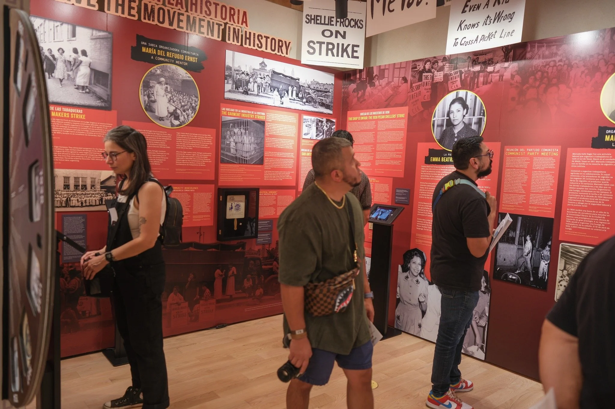 Museum exhibit with historical photos and information panels about workers' strikes and social movements, with visitors observing and reading the displays.