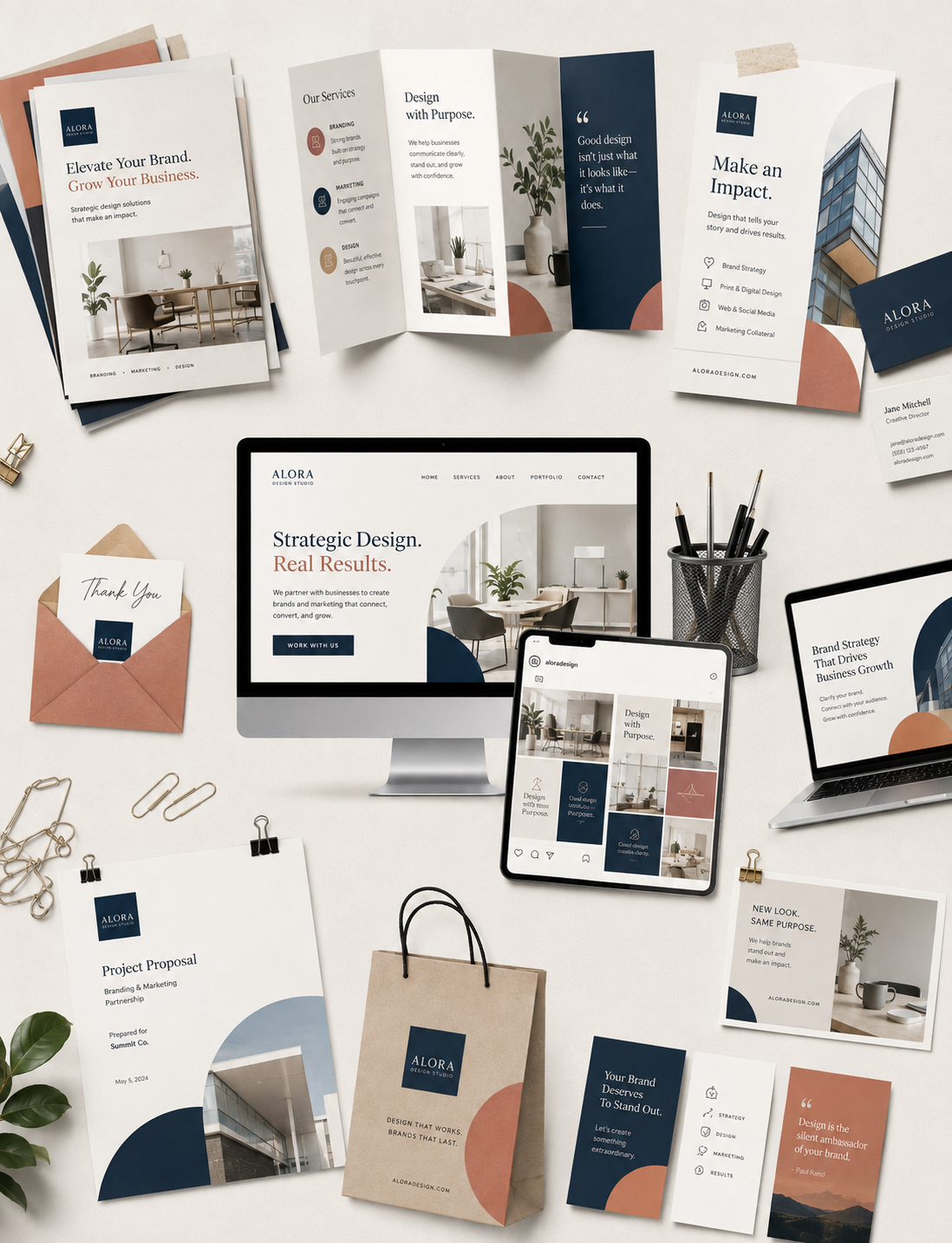 A collection of branding, marketing, and design marketing materials on a white desk, including brochures, business cards, a computer monitor, tablets, a tote bag, envelopes, and stationery, all featuring the Alora Design Studio logo and branding.