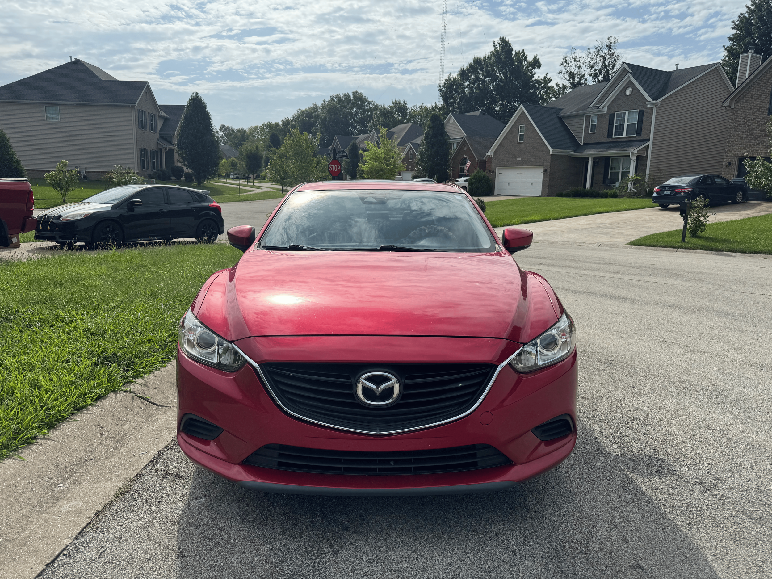 Red Mazda car on display with clear headlights after a headlight restoration service