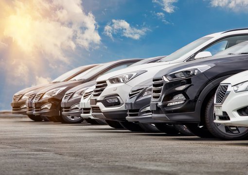 Lineup of various new cars parked outdoors on a sunny day.