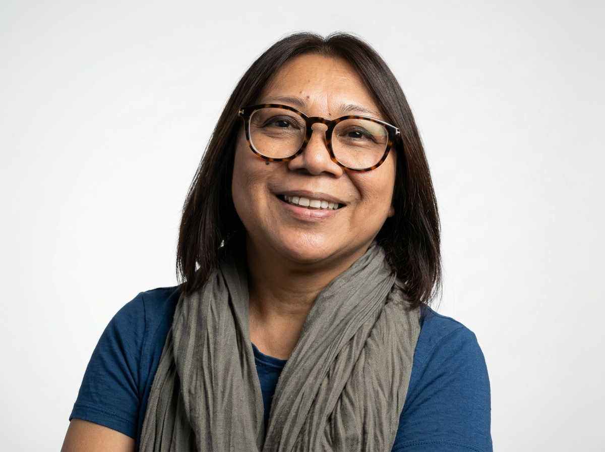 Smiling woman with glasses and a gray scarf posing against a white background.