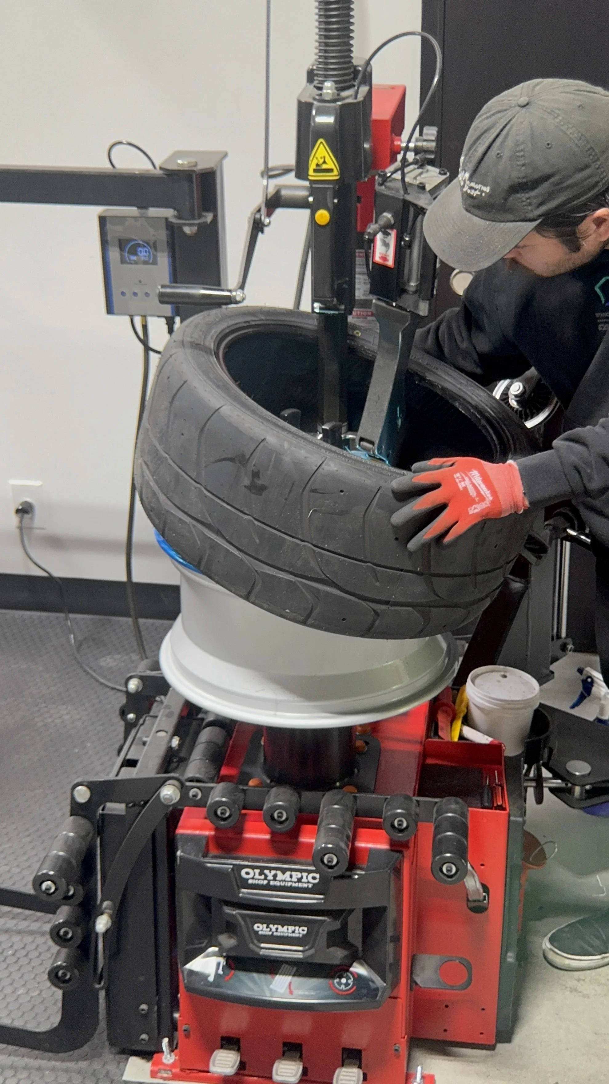 A person using a tire mounting machine to install a tire onto a wheel rim in a workshop.