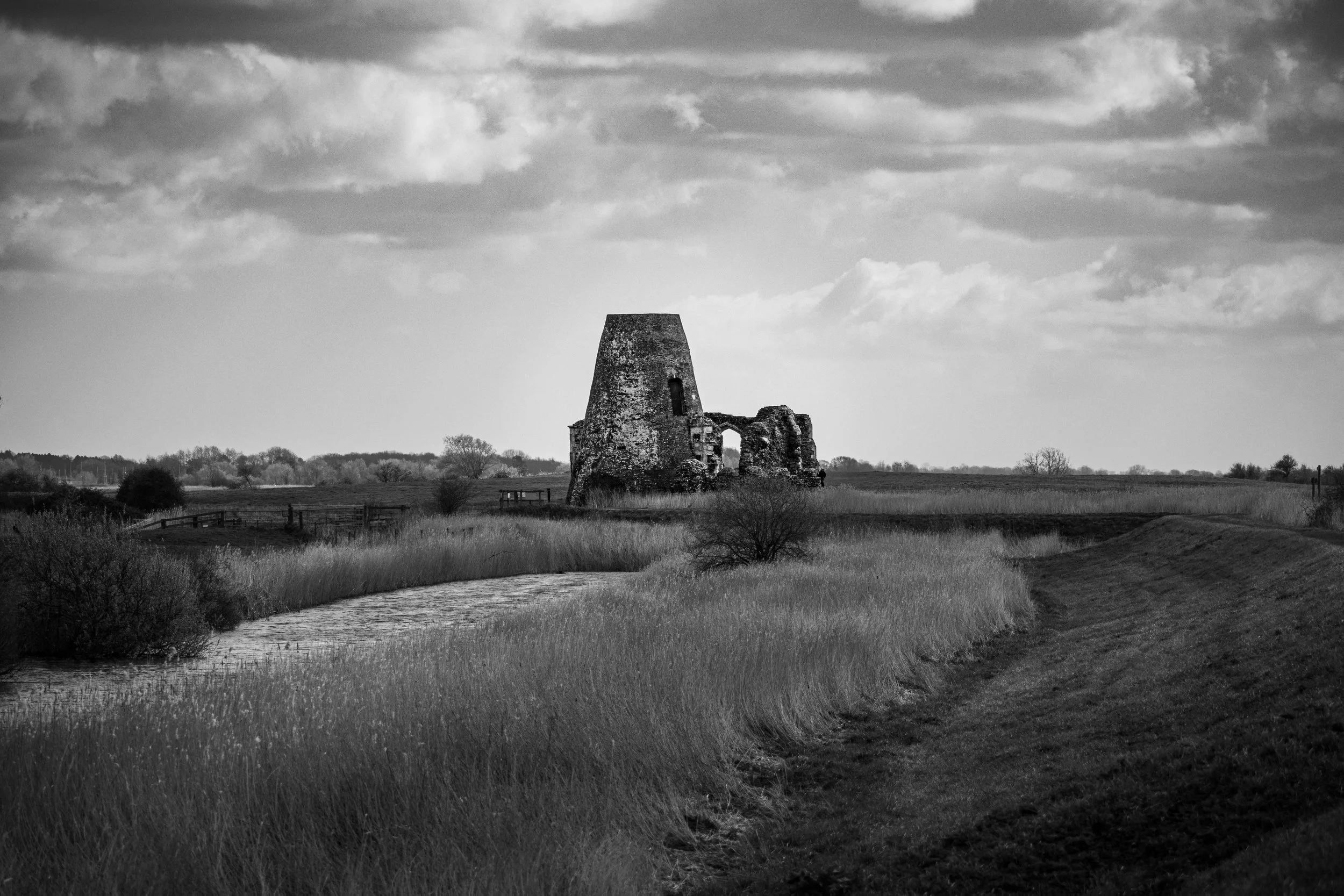 Black and white photograph of the ruins of St Benet's Abbey in the Norfolk Broads, surrounded by the River Bure and rural landscape.