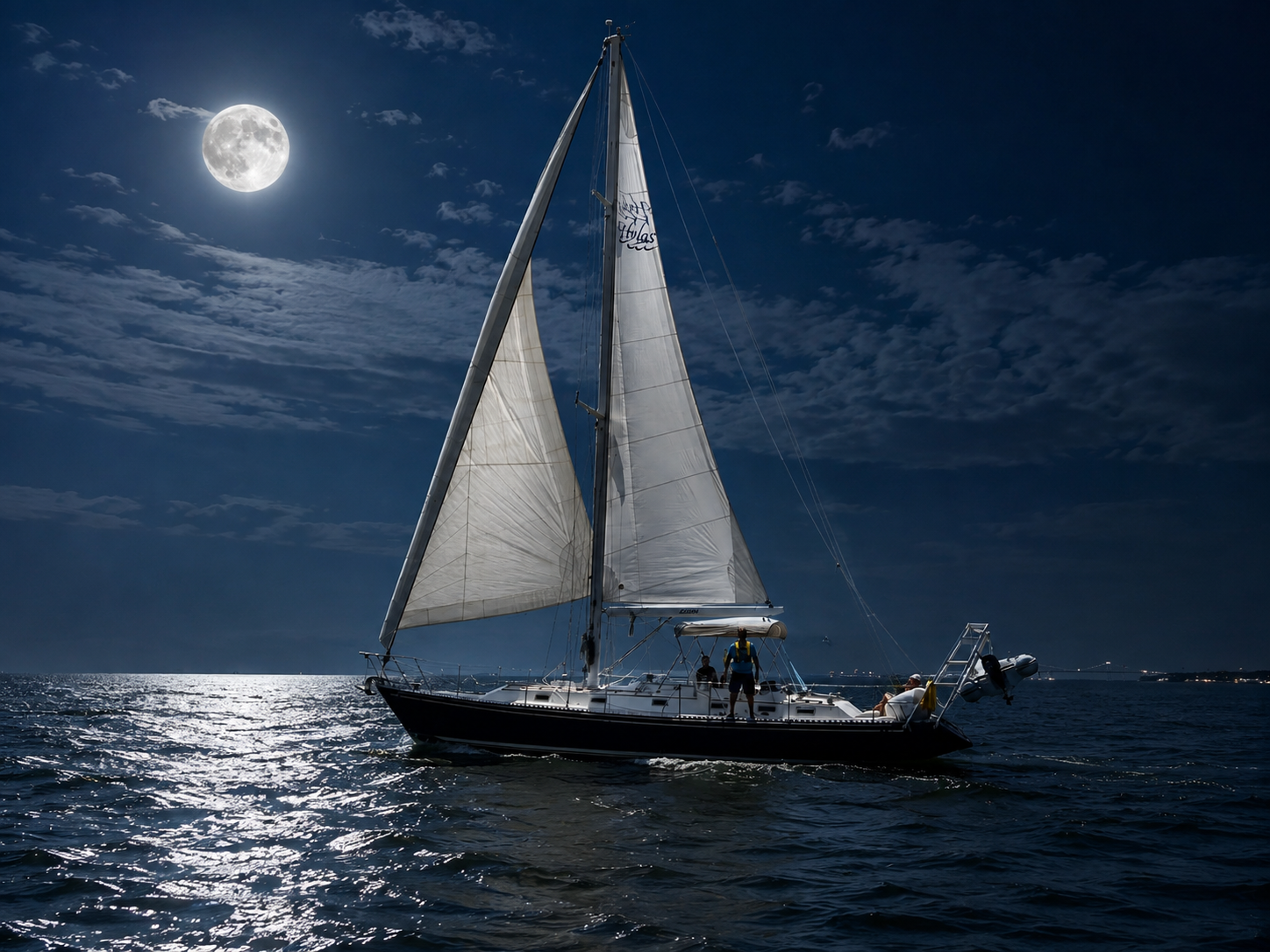 Kadima Sails sailboat on calm water during a full moon sailing experience at night.