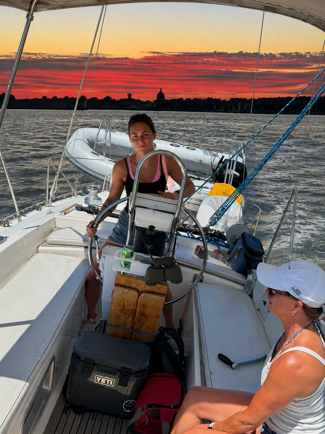 Kadima Sails image of two women enjoying a sunset sail with a waterfront skyline in the background.