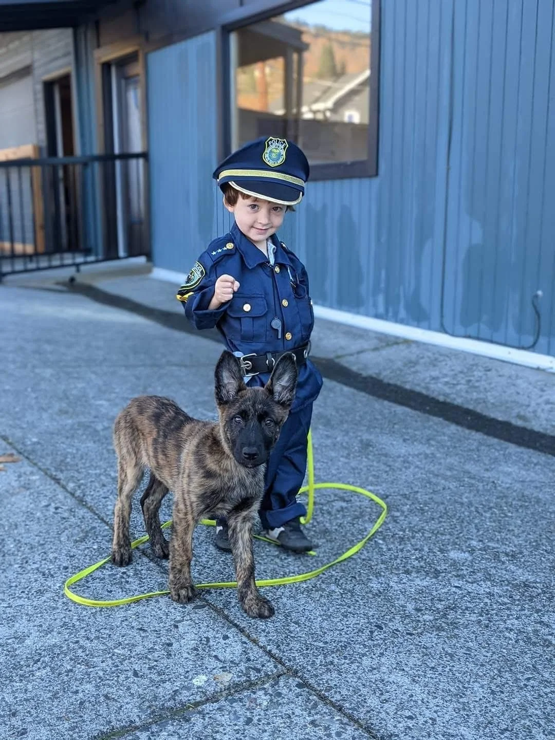 Arlo in a police costume standing with puppy Blaze