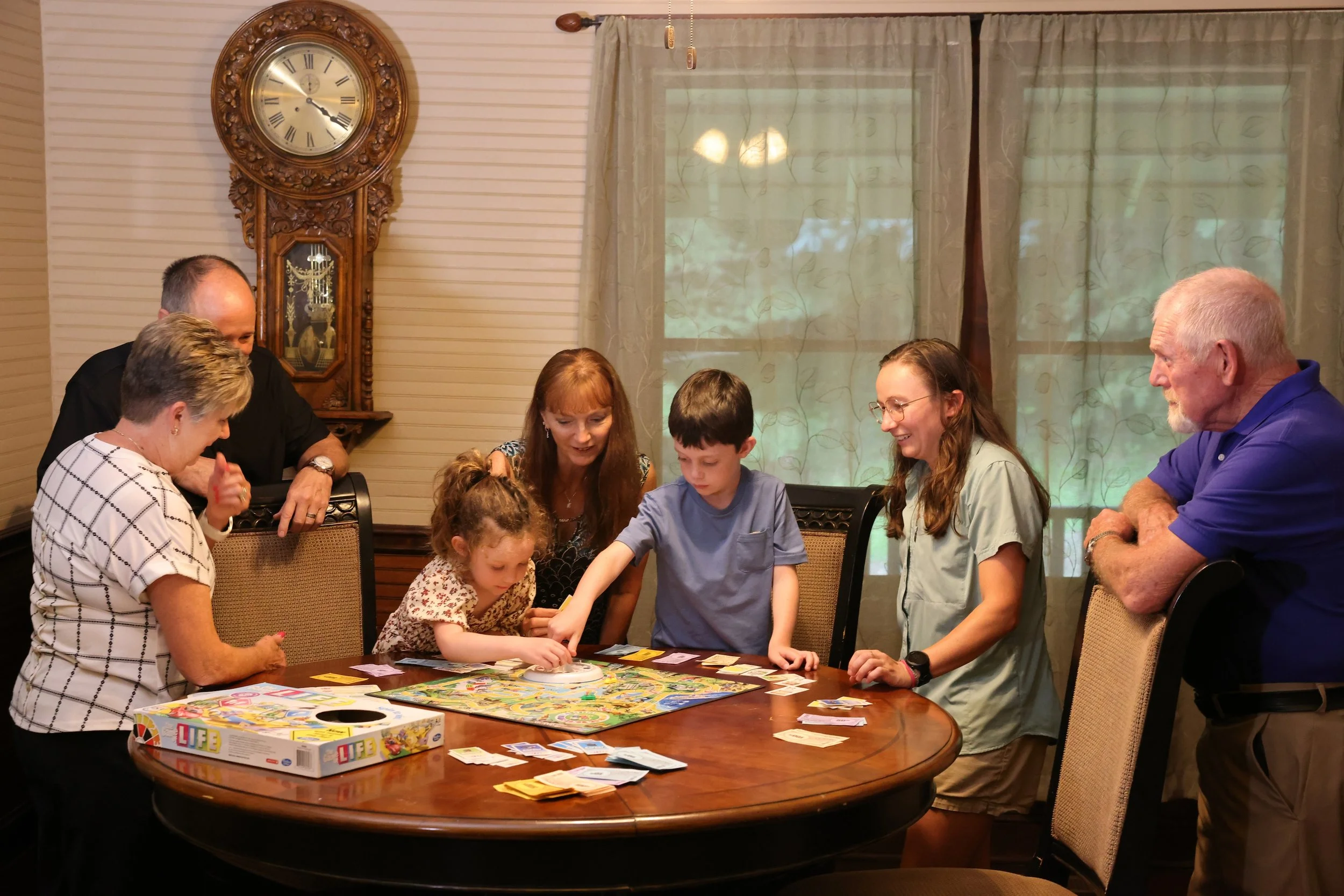 Family playing a board game together inside Stines House at Twin Willows.