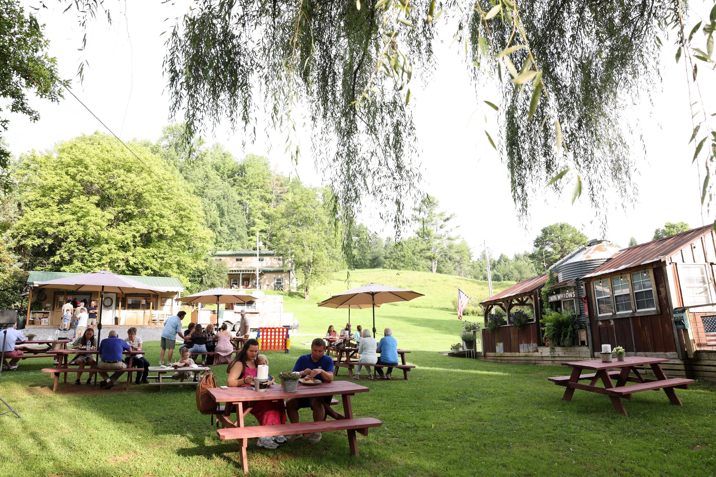 Guests dining outdoors under the willow trees at Twin Willows.
