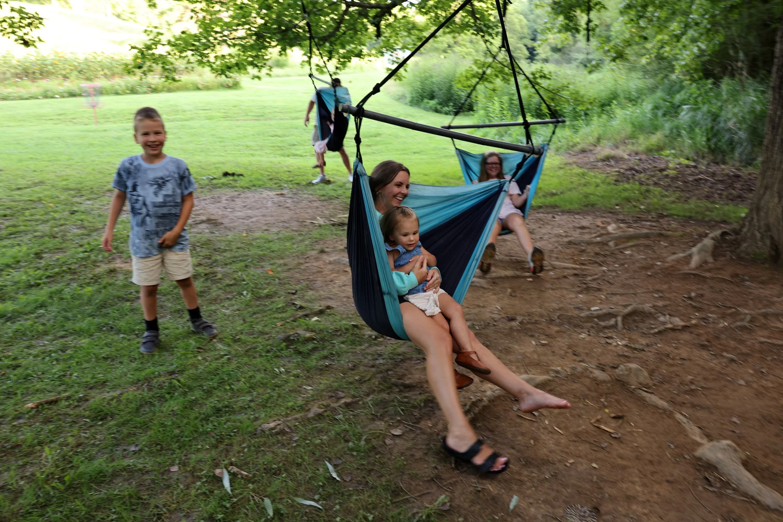 Guests relaxing in hammock chairs beneath the trees at Twin Willows.