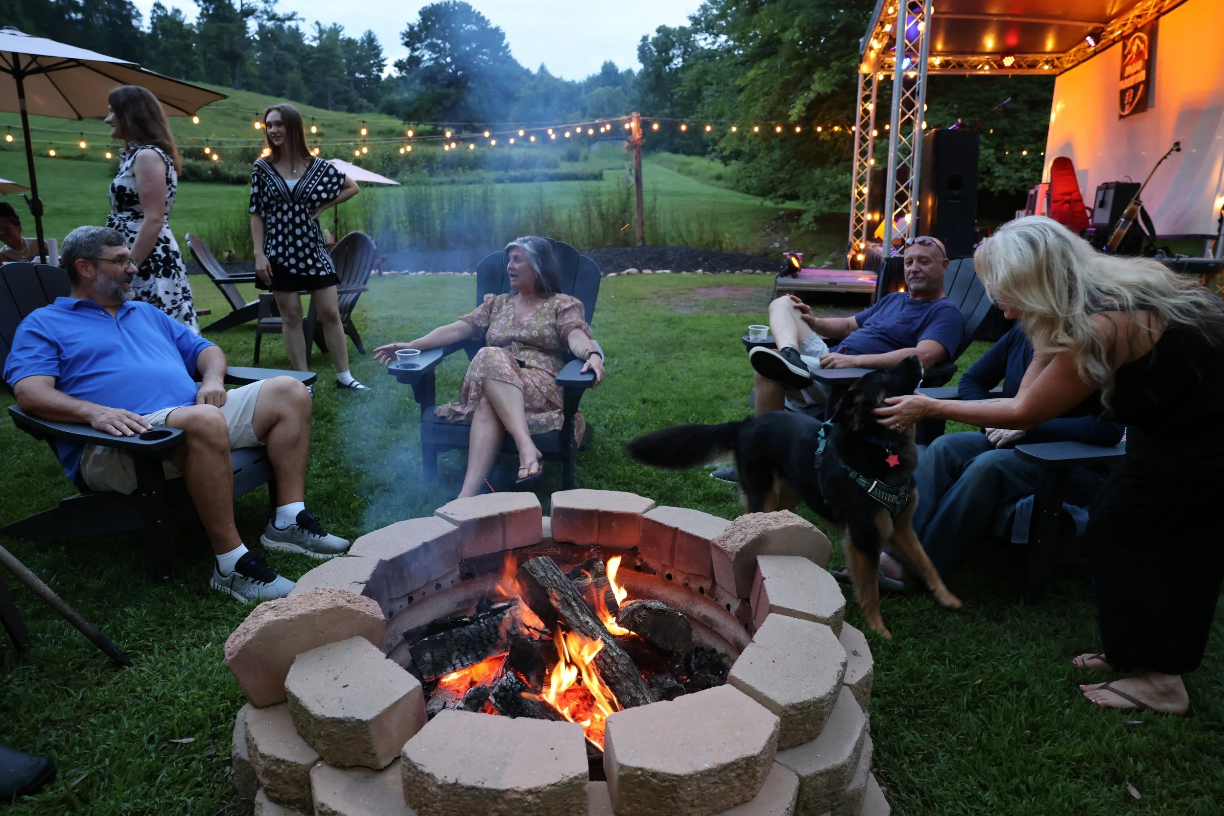 Friends gathered around a fire pit at Twin Willows at dusk.