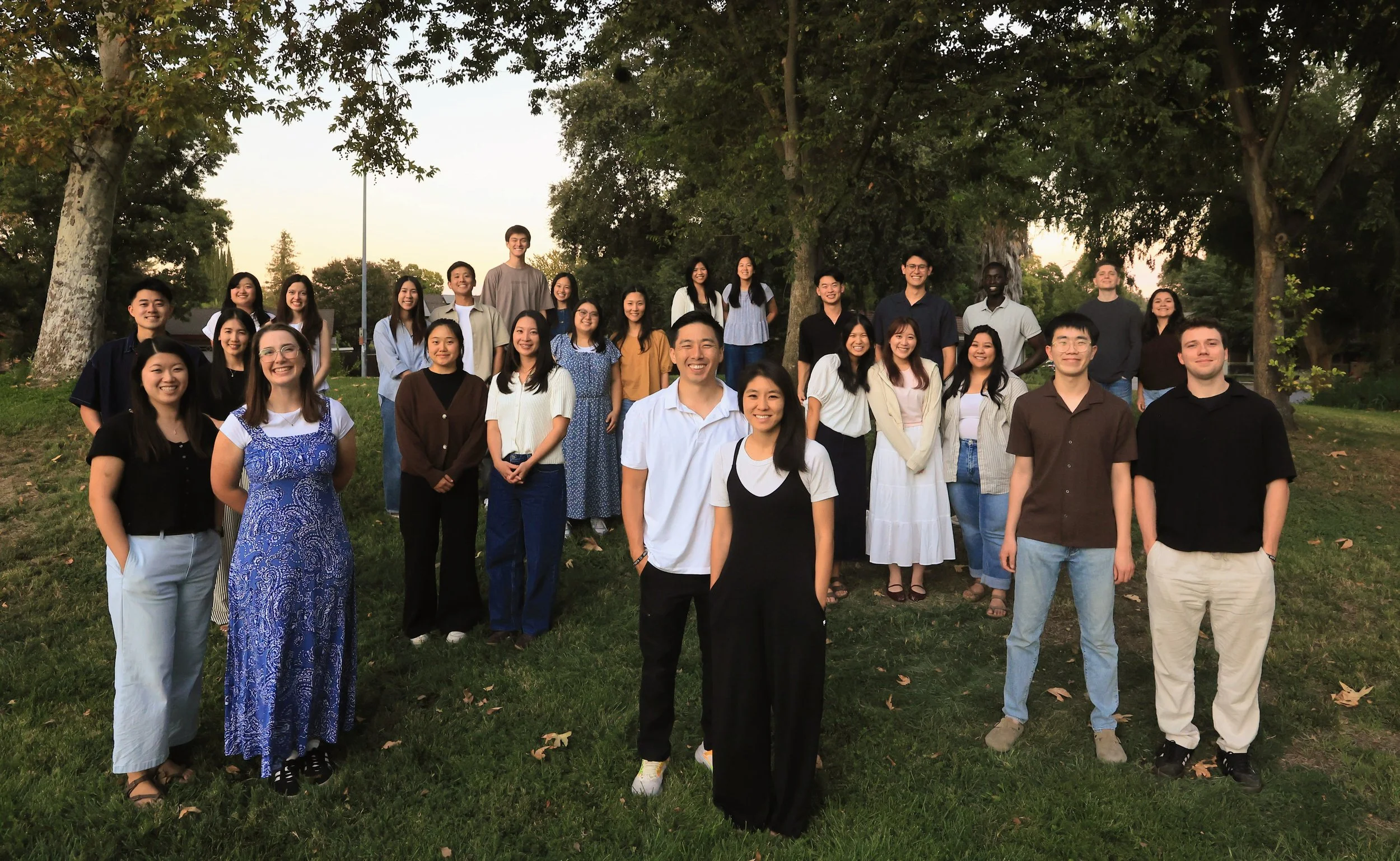 Group of Klesis Christian Fellowship mentors standing and smiling outdoors in a park with trees in the background.