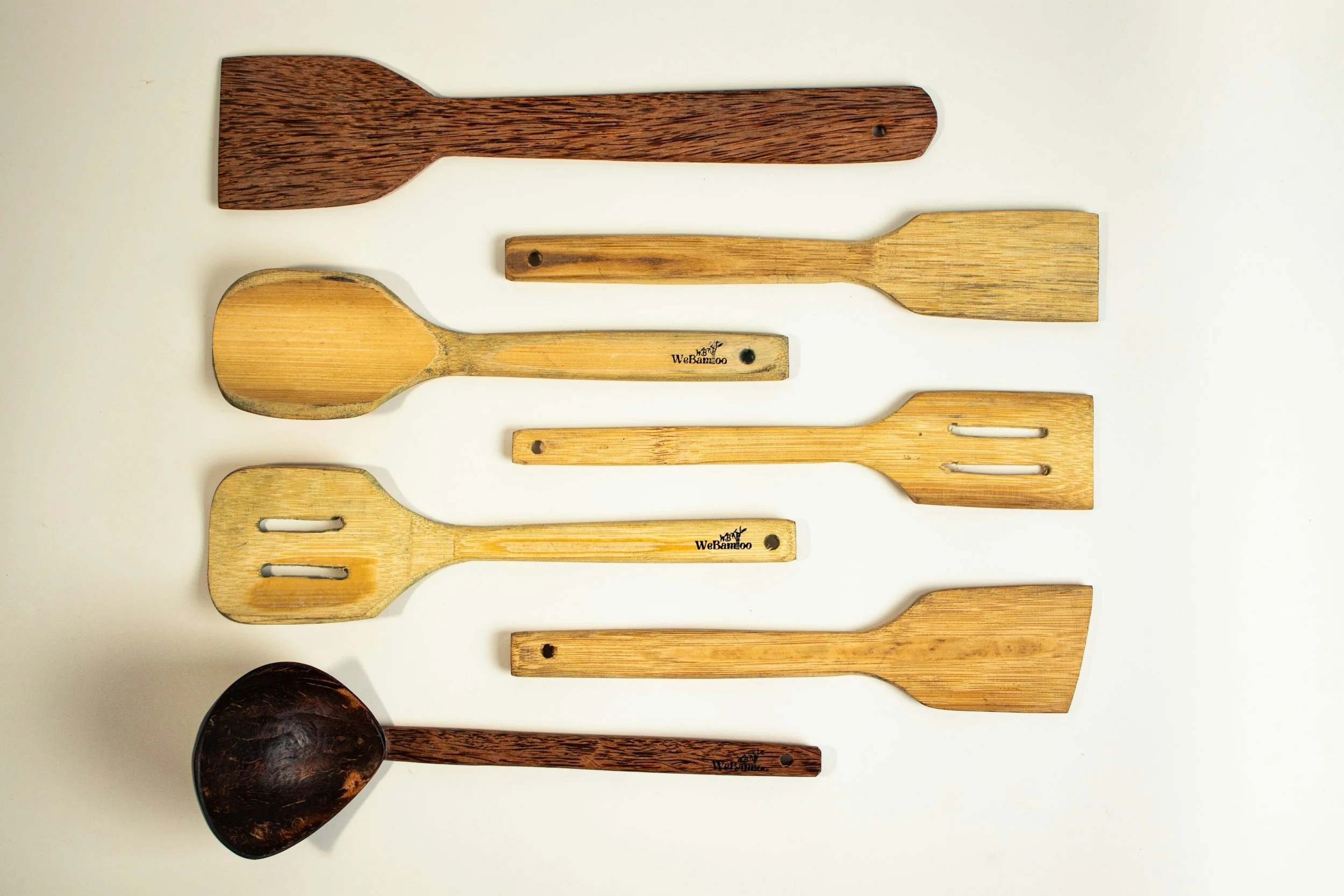 Various wooden kitchen utensils arranged on a white surface, including spoons and spatulas of different shapes and sizes.
