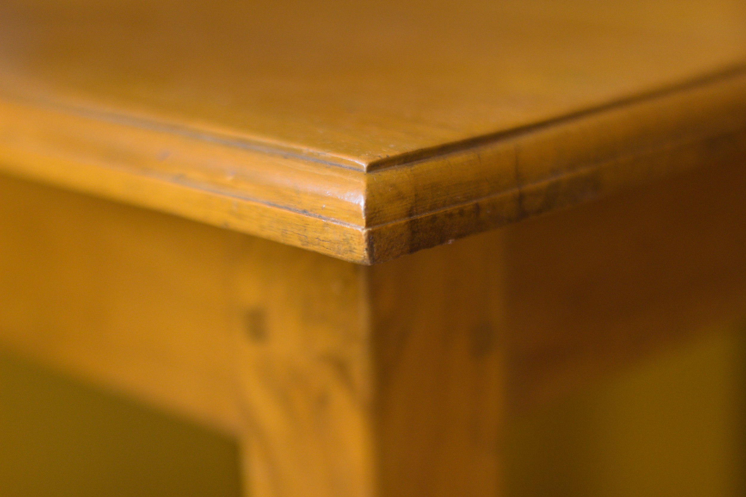 Close-up of a wooden piece with a smooth finish and rounded edge, showing some wear and tear.