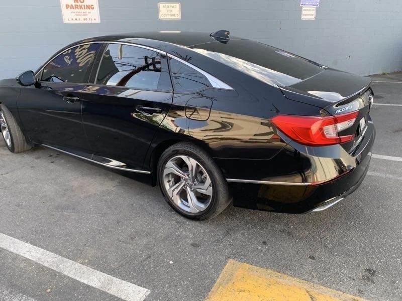 Black Honda Accord parked in a parking lot with visible signs and a yellow parking block.