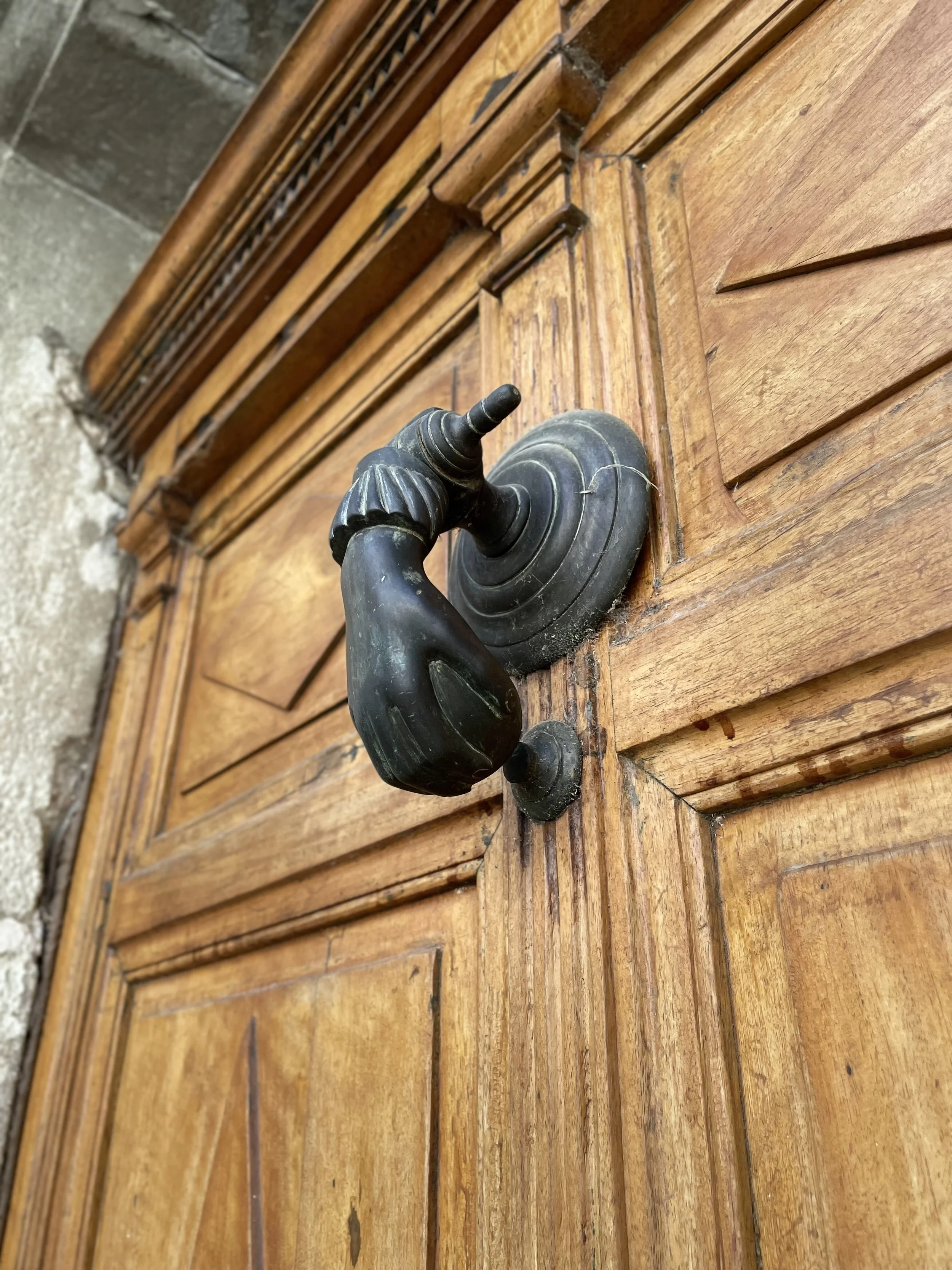 Close-up of an ornate black door handle on a wooden door with detailed molding.