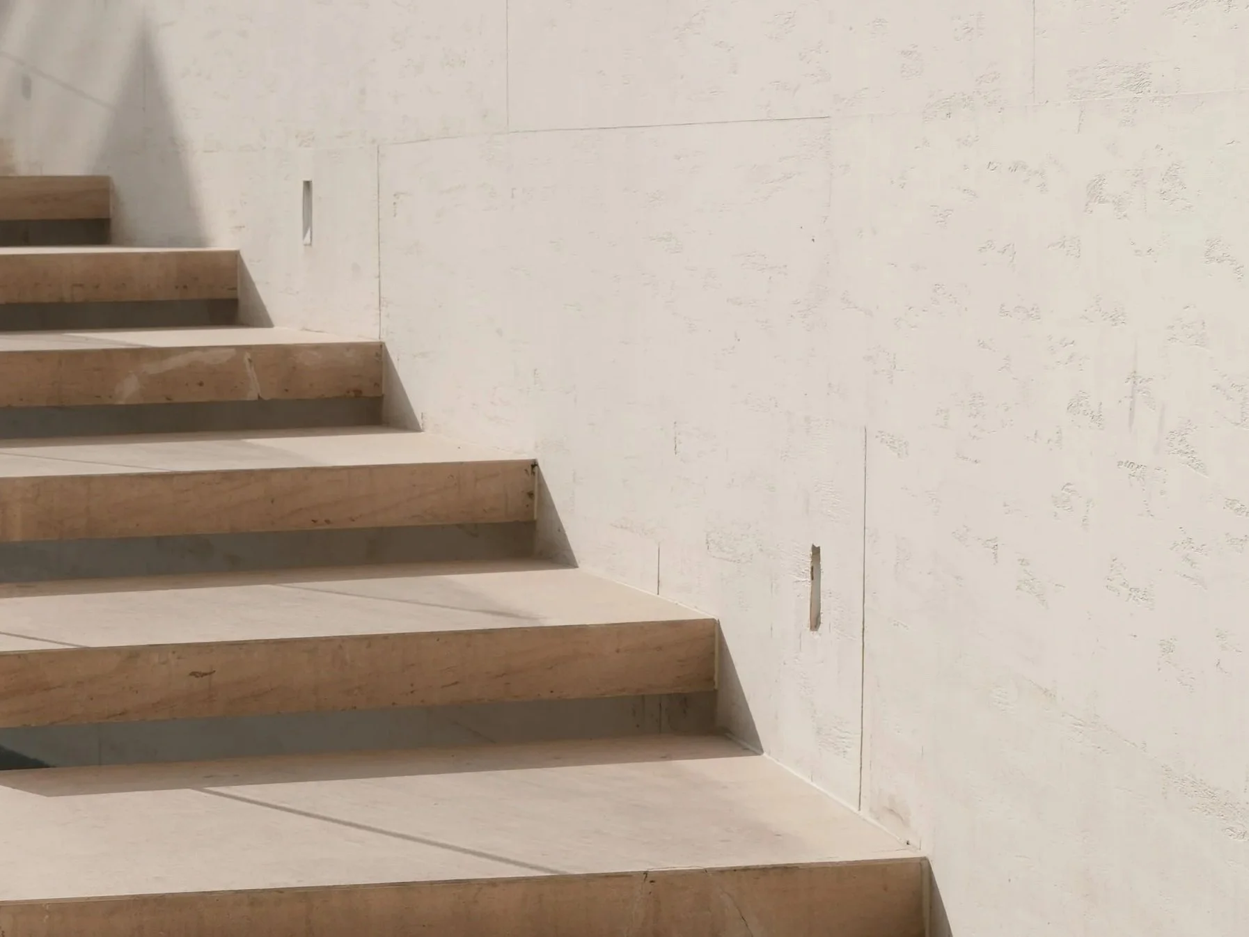 Photo of a staircase with unfinished steps and a white wall with visible construction marks.