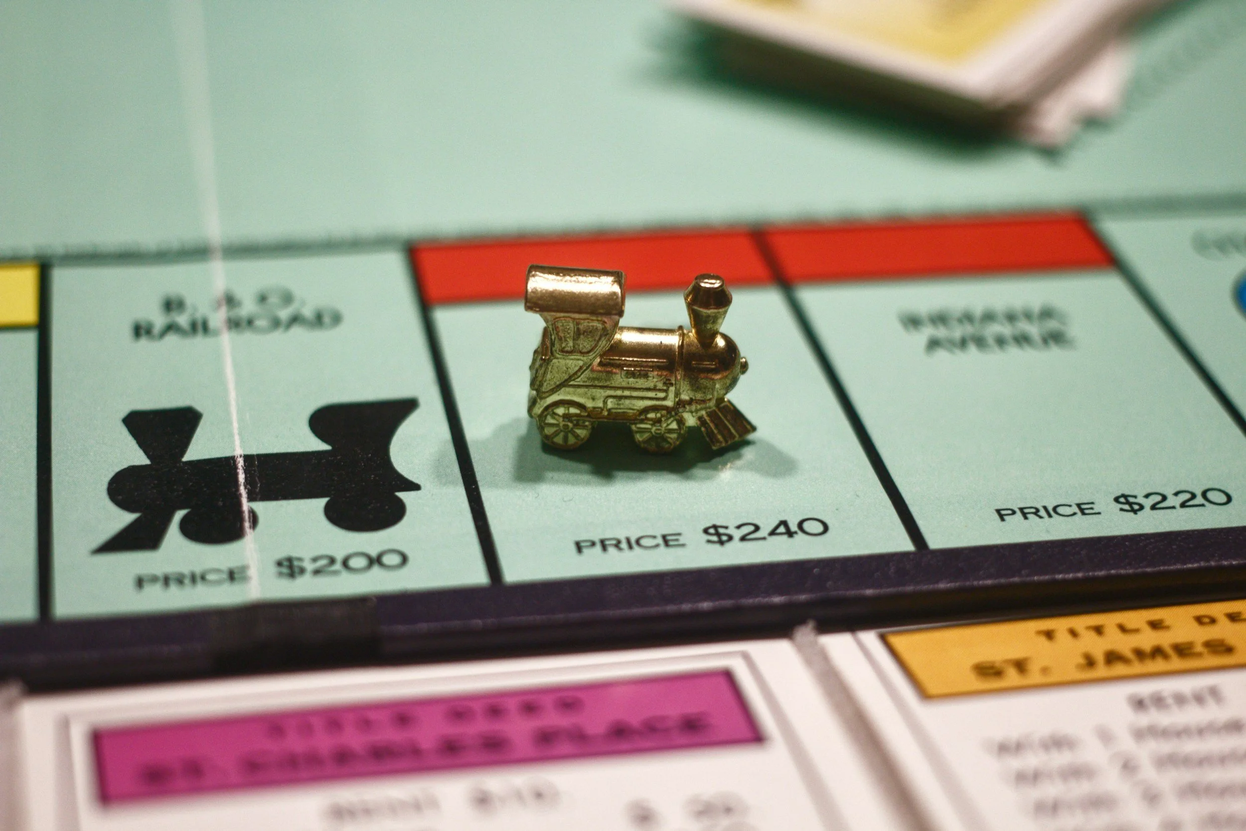 Close-up of a small, shiny gold train playing piece on a Monopoly game board.