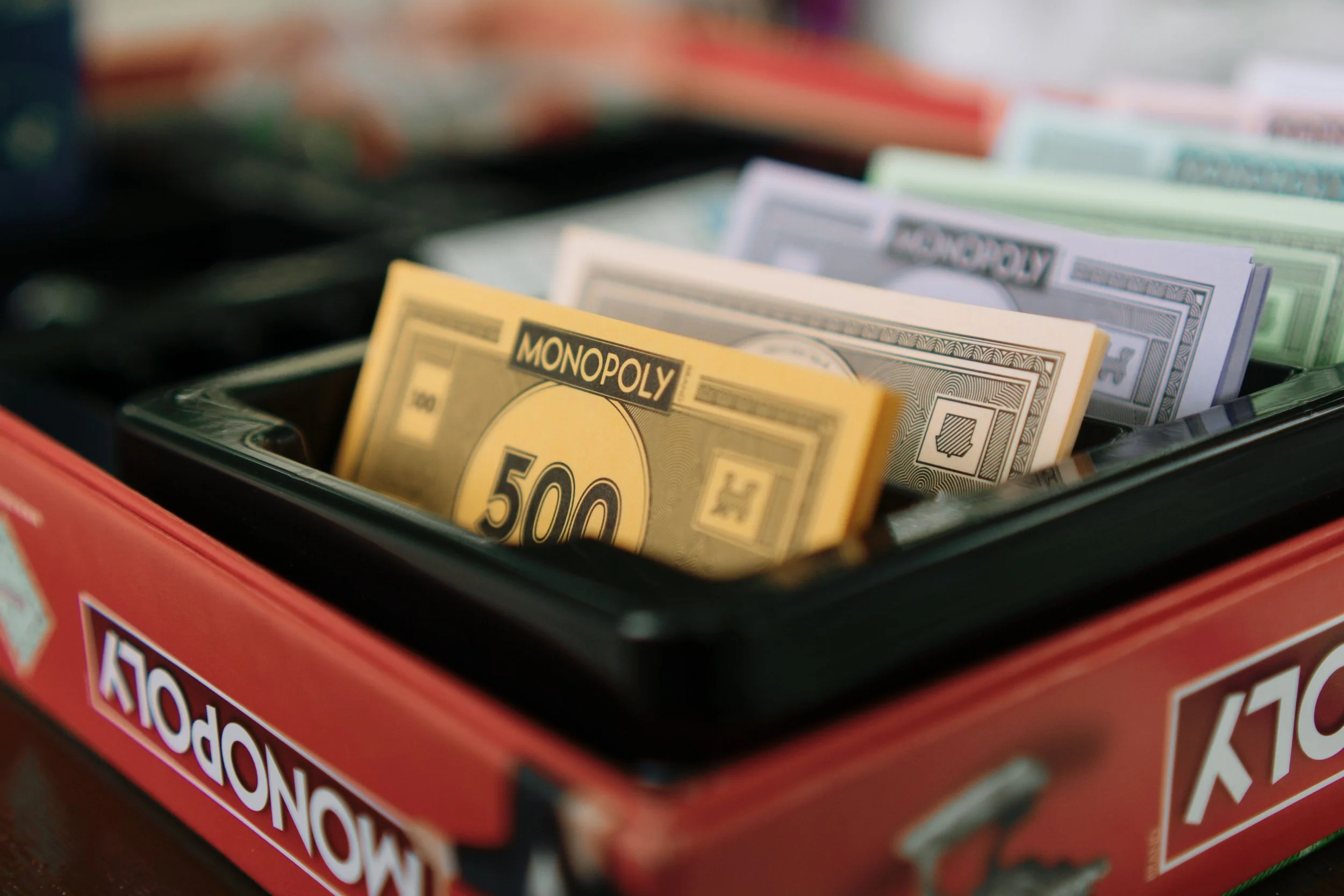 Close-up of a Monopoly game box with money, including a 500-dollar bill visible.