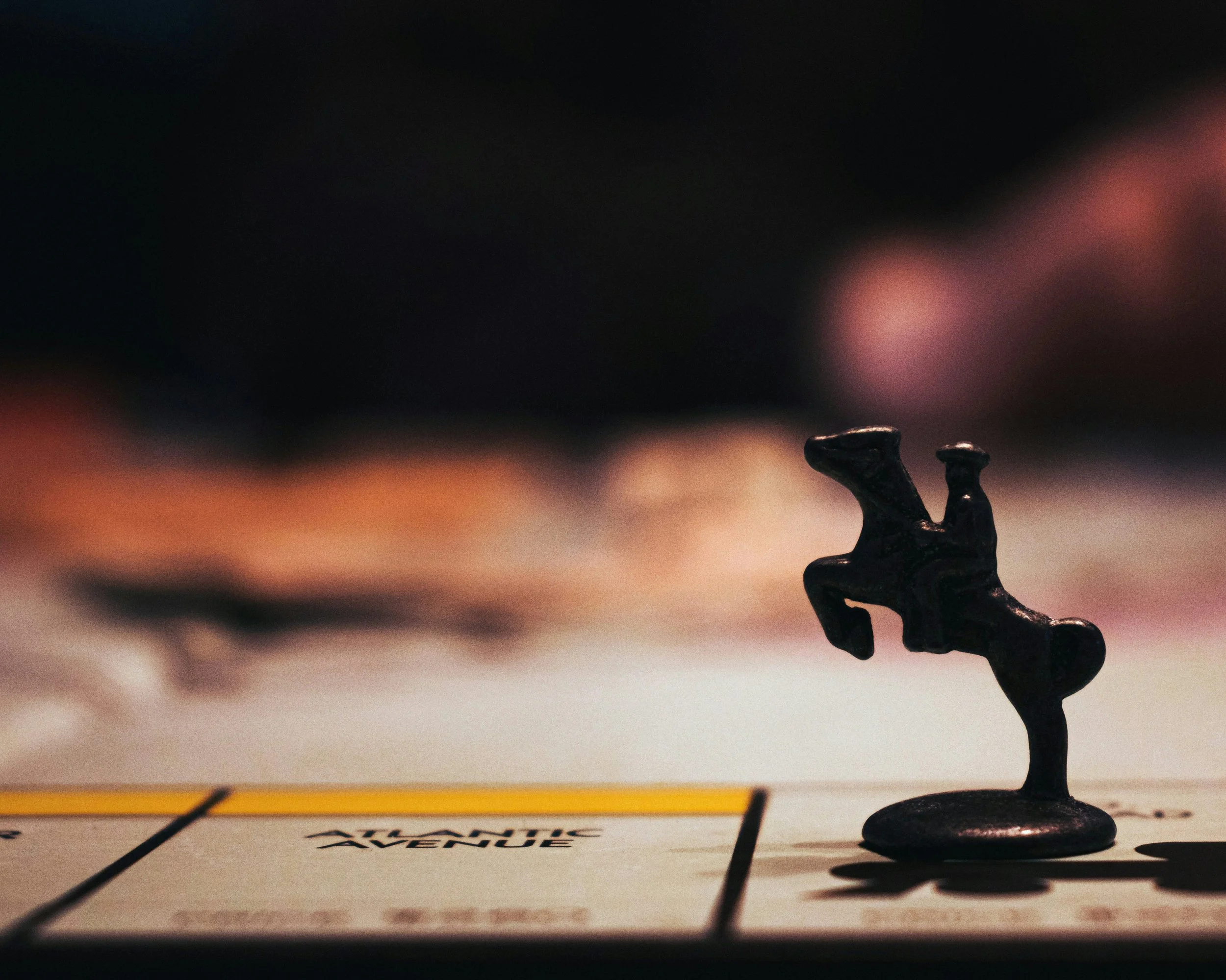 Close-up of a miniature trophy resembling a person with arms raised, placed on a surface with a partially visible map or game board underneath.