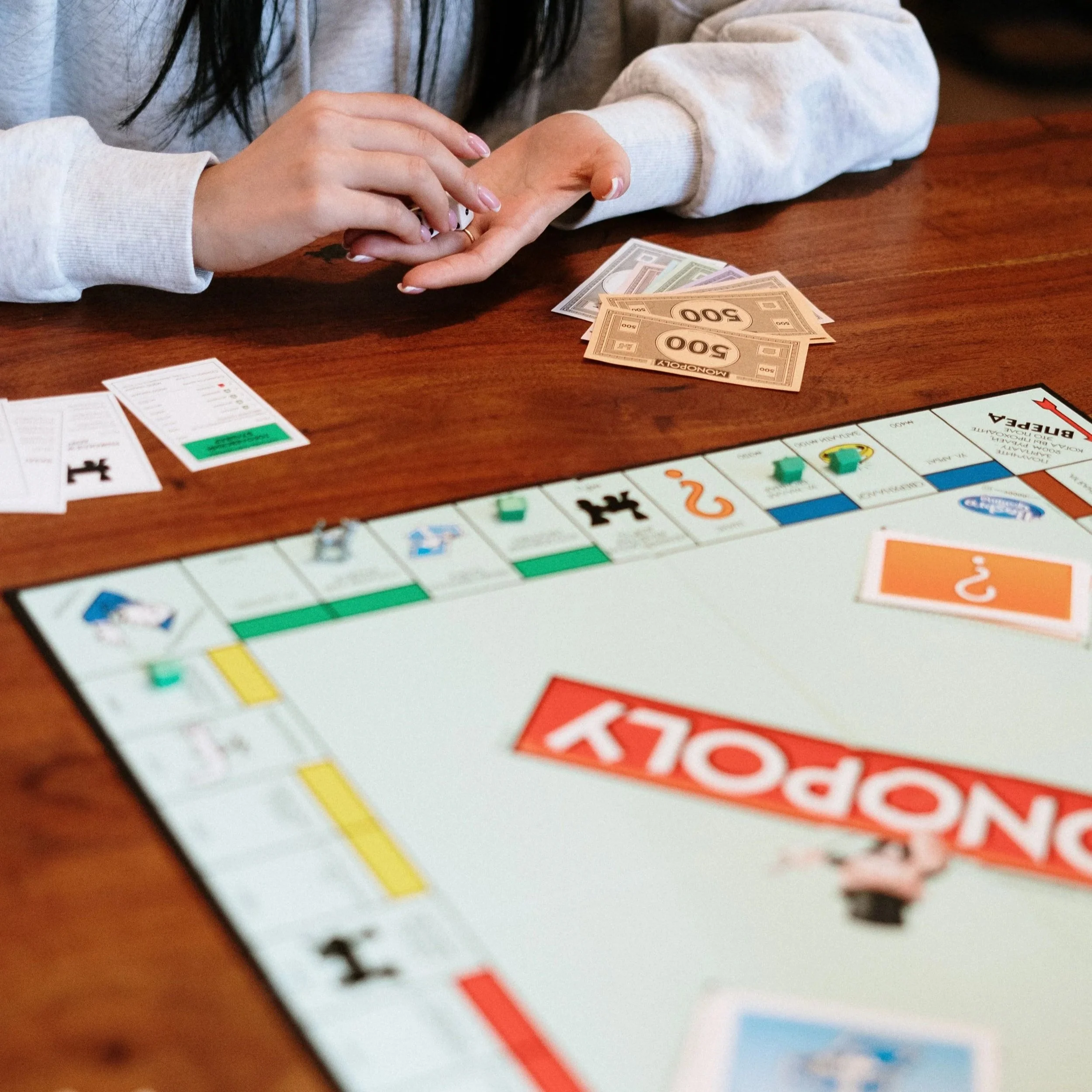 Two people playing Monopoly, with one person placing a $500 bill on the other's open palm.