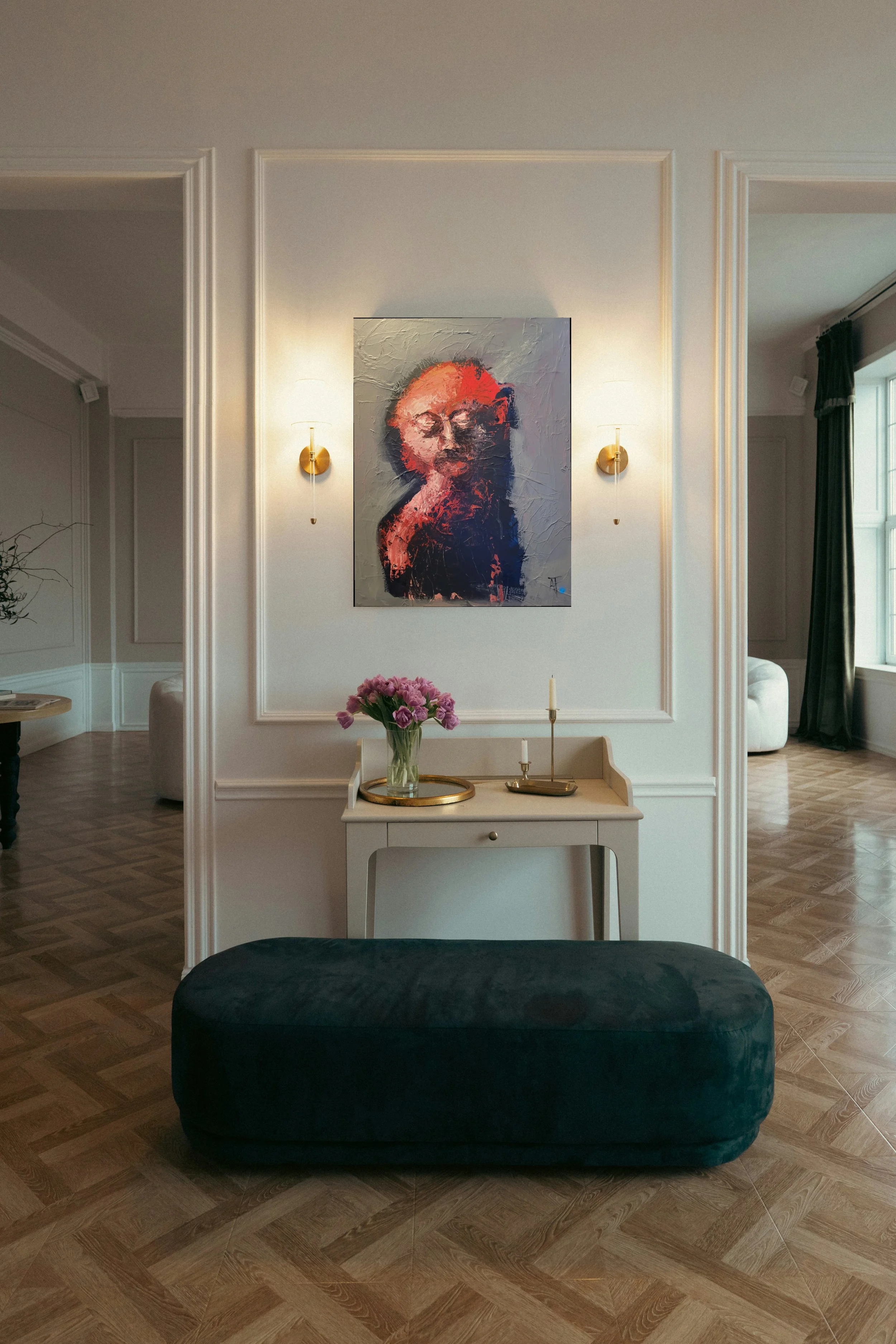 Intérieur d'une pièce élégante avec une peinture abstraite au mur, une table avec un vase de fleurs, des bougies, et un fauteuil ou un canapé en arrière-plan, éclairé par deux appliques murales et une grande fenêtre.