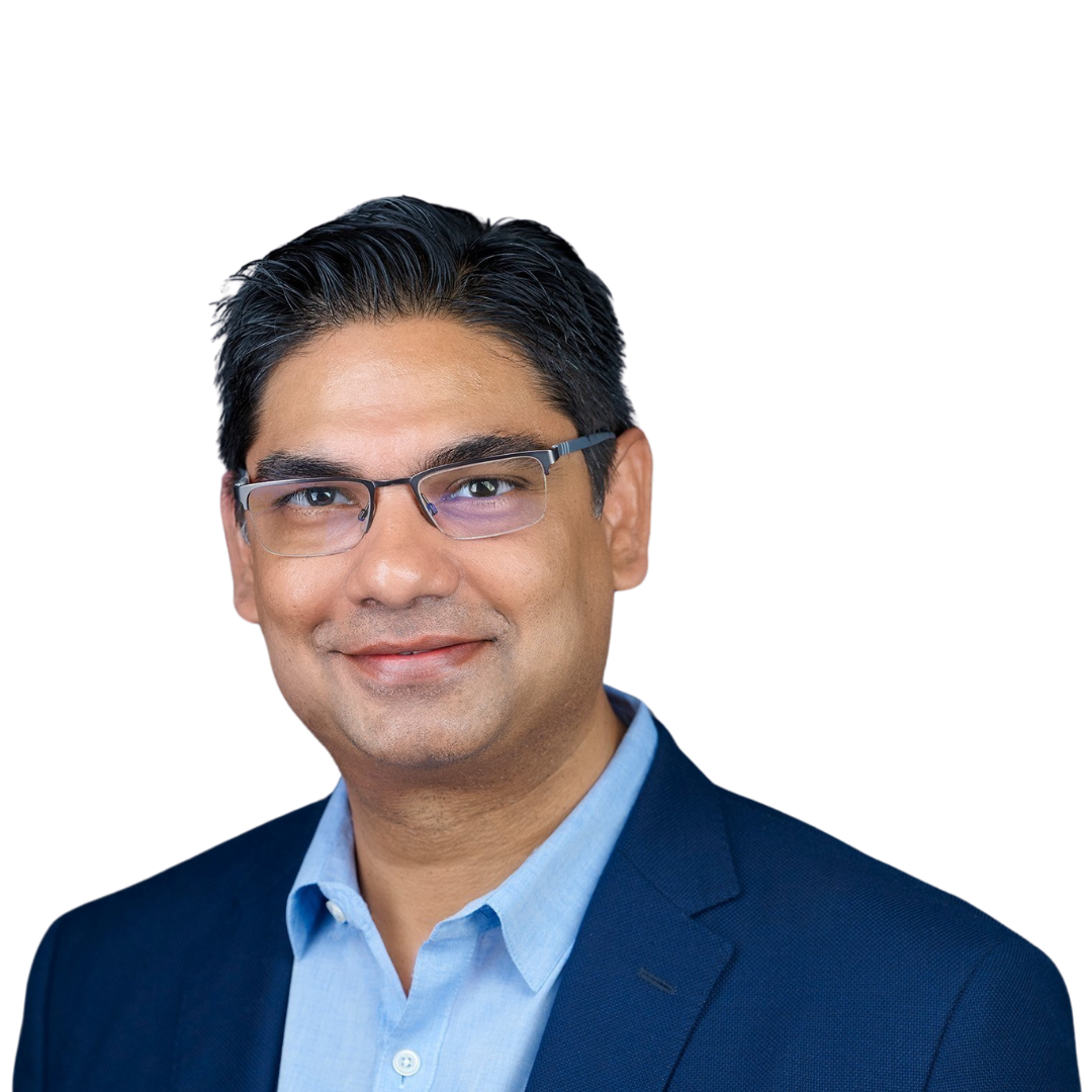 Portrait of a man in a blue suit and glasses smiling against a plain background.